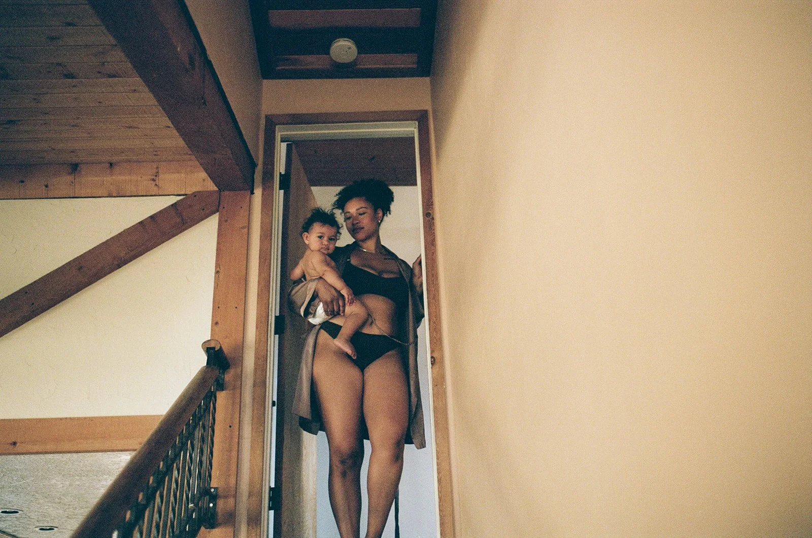 mother holds her baby standing at the top of a stairway while modeling for a workshop 