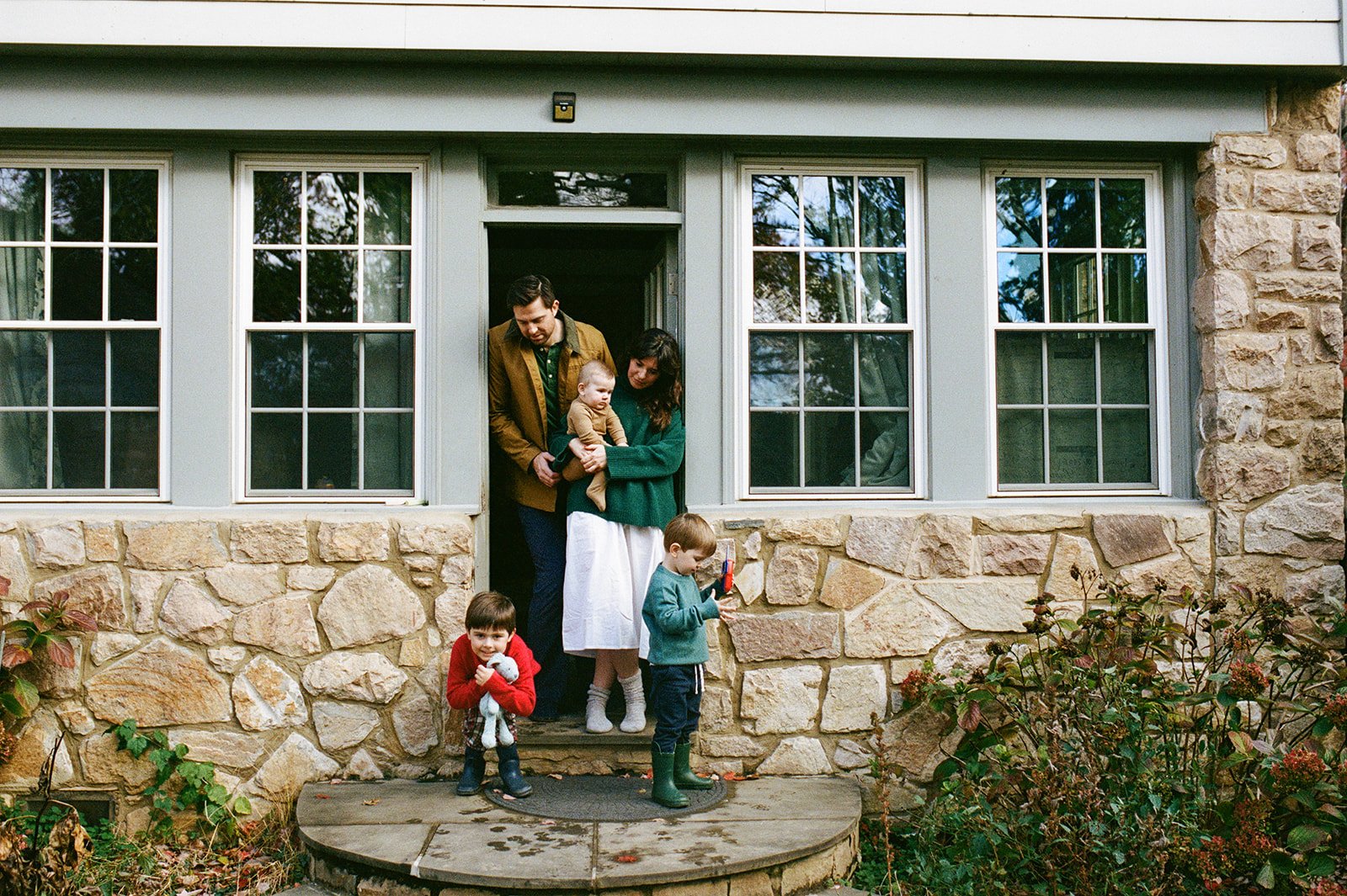 Family of five standing in the doorway and front step of their home