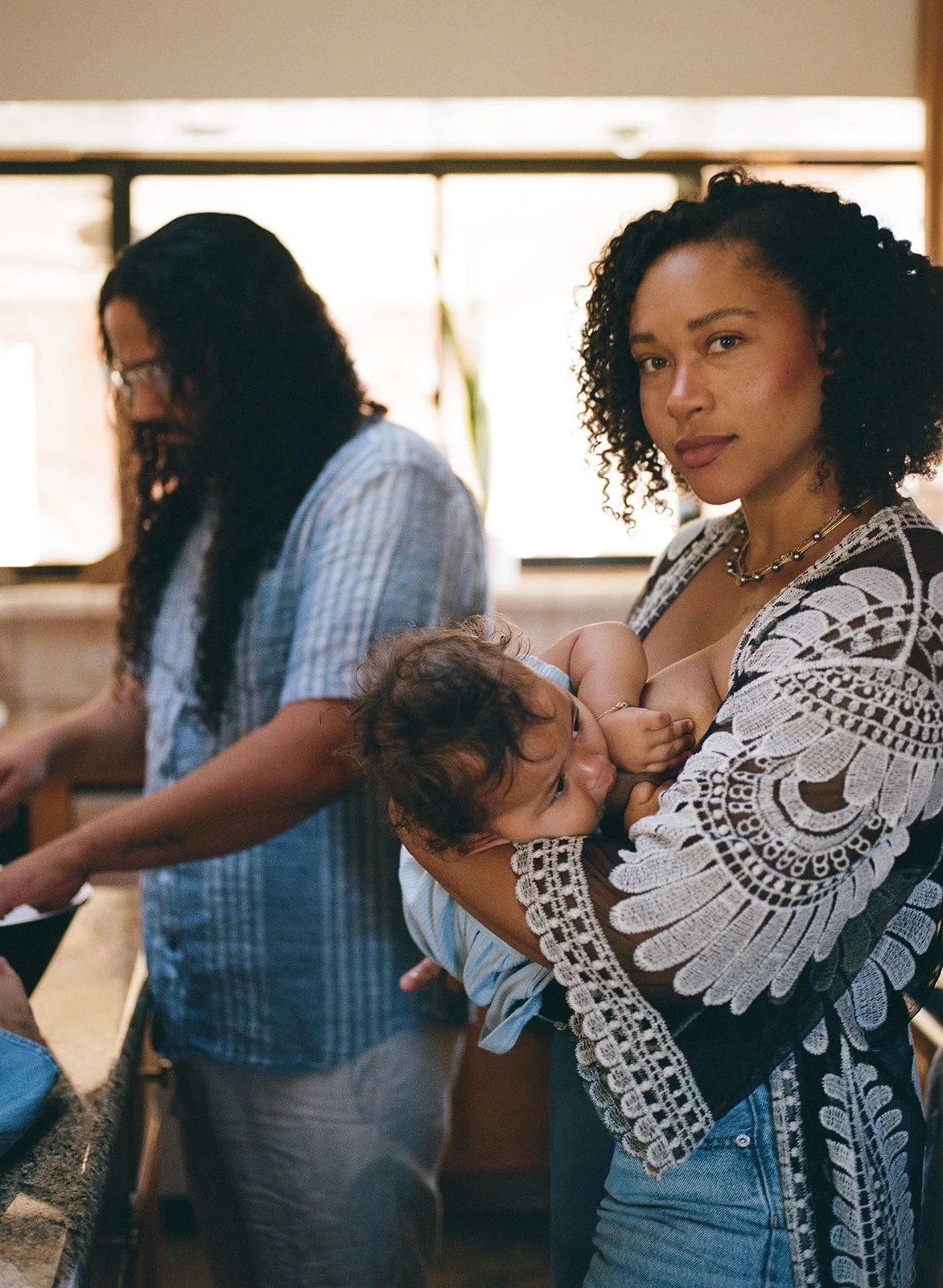 woman breastfeeding her infant looks at the camera 