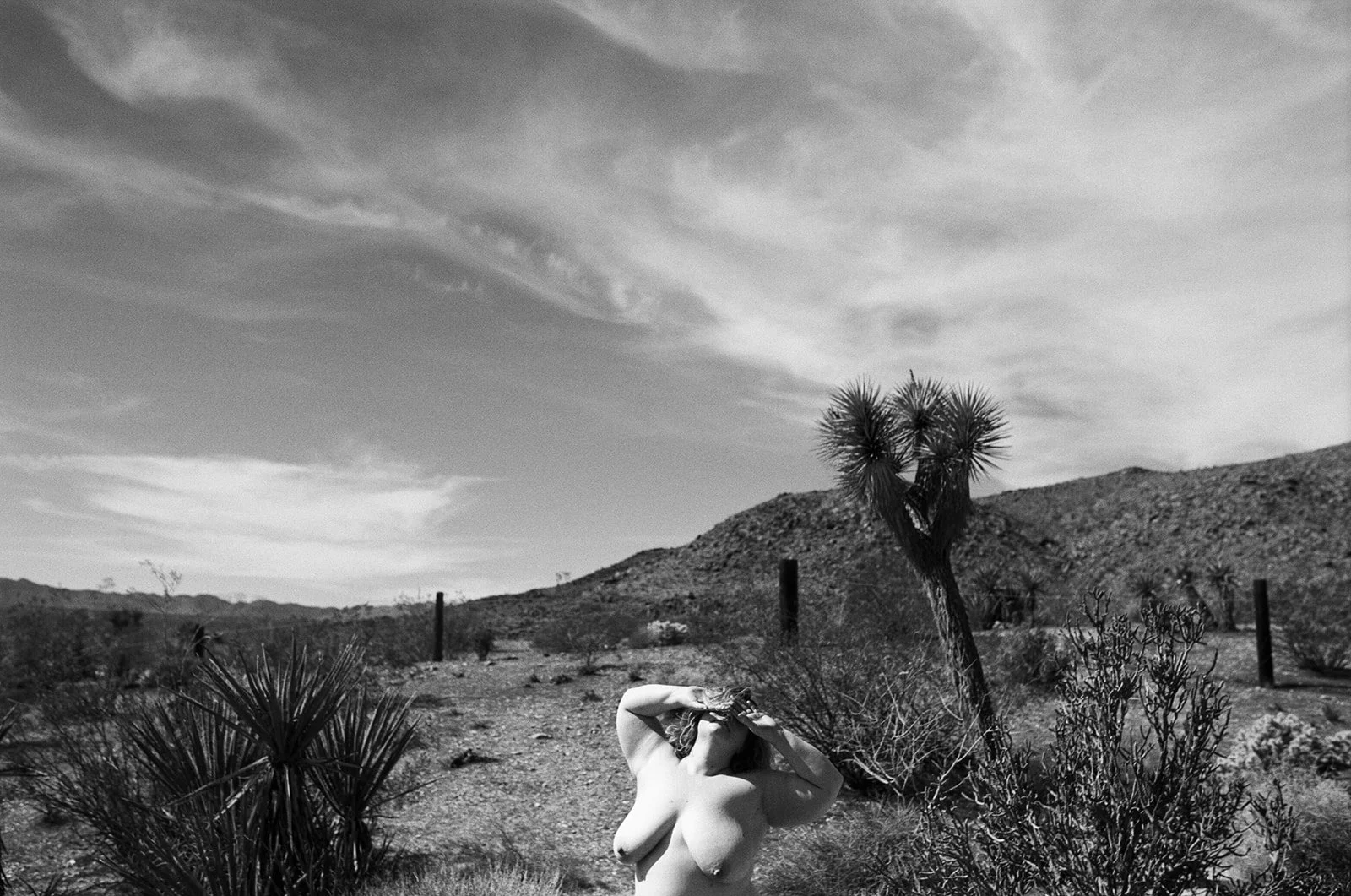 black and white image of a topless woman in the desert 