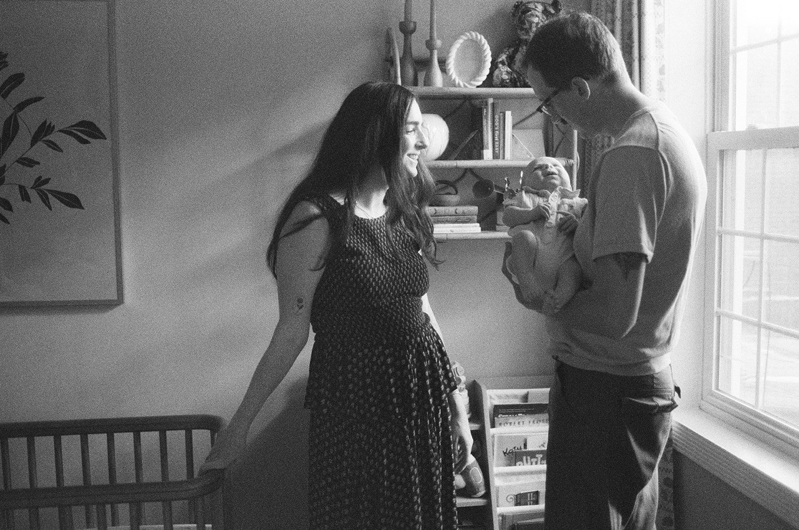 family portrait of parents and newborn in the nursery on black and white film 