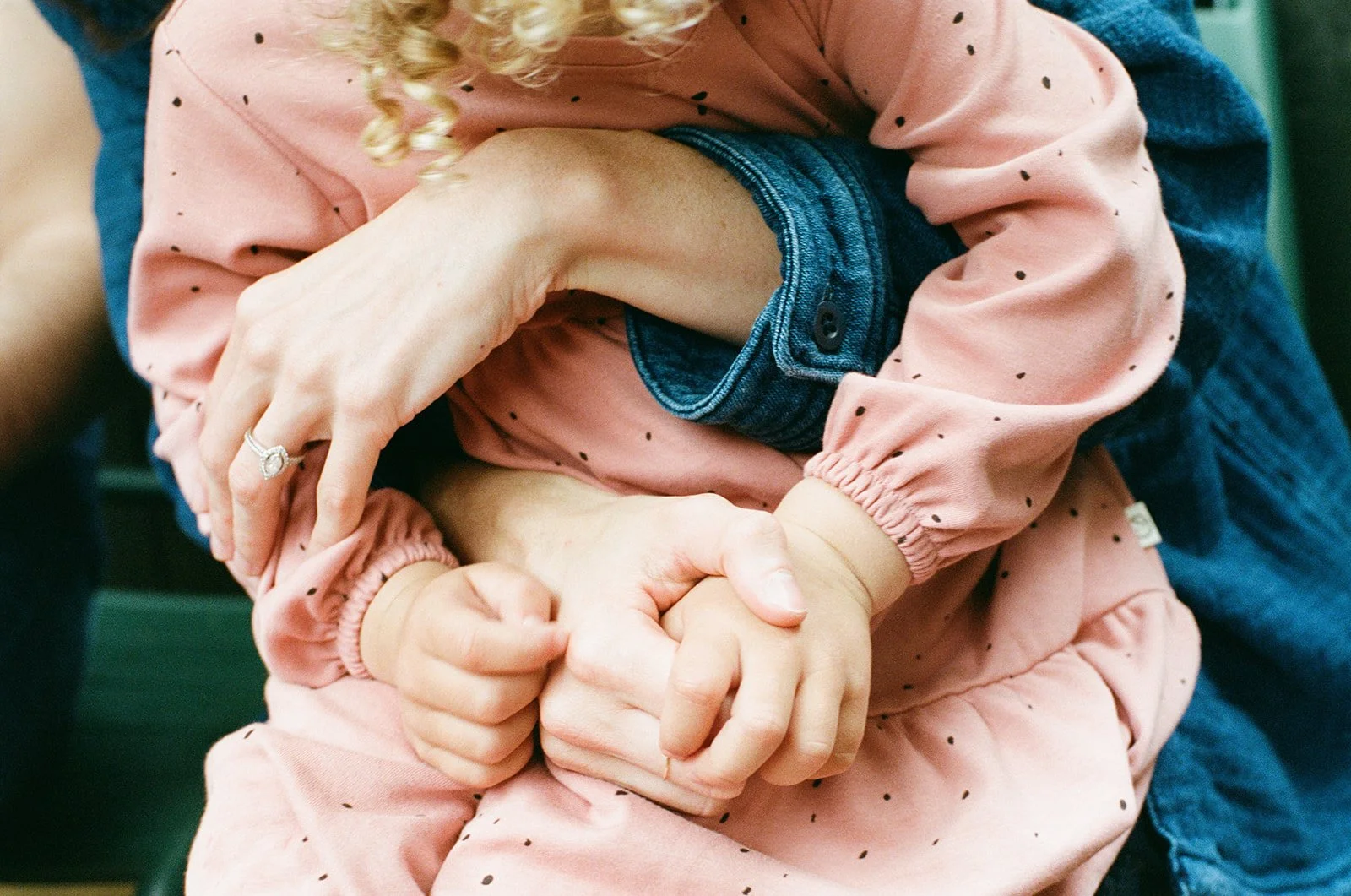 close up photograph taken on film of a mother and child's fingers and hands intertwined with one another 