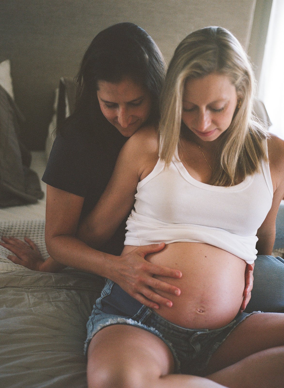 expectant mothers look at and hold mom's pregnant belly in anticipation during maternity session with Rachel Larsen Weaver 