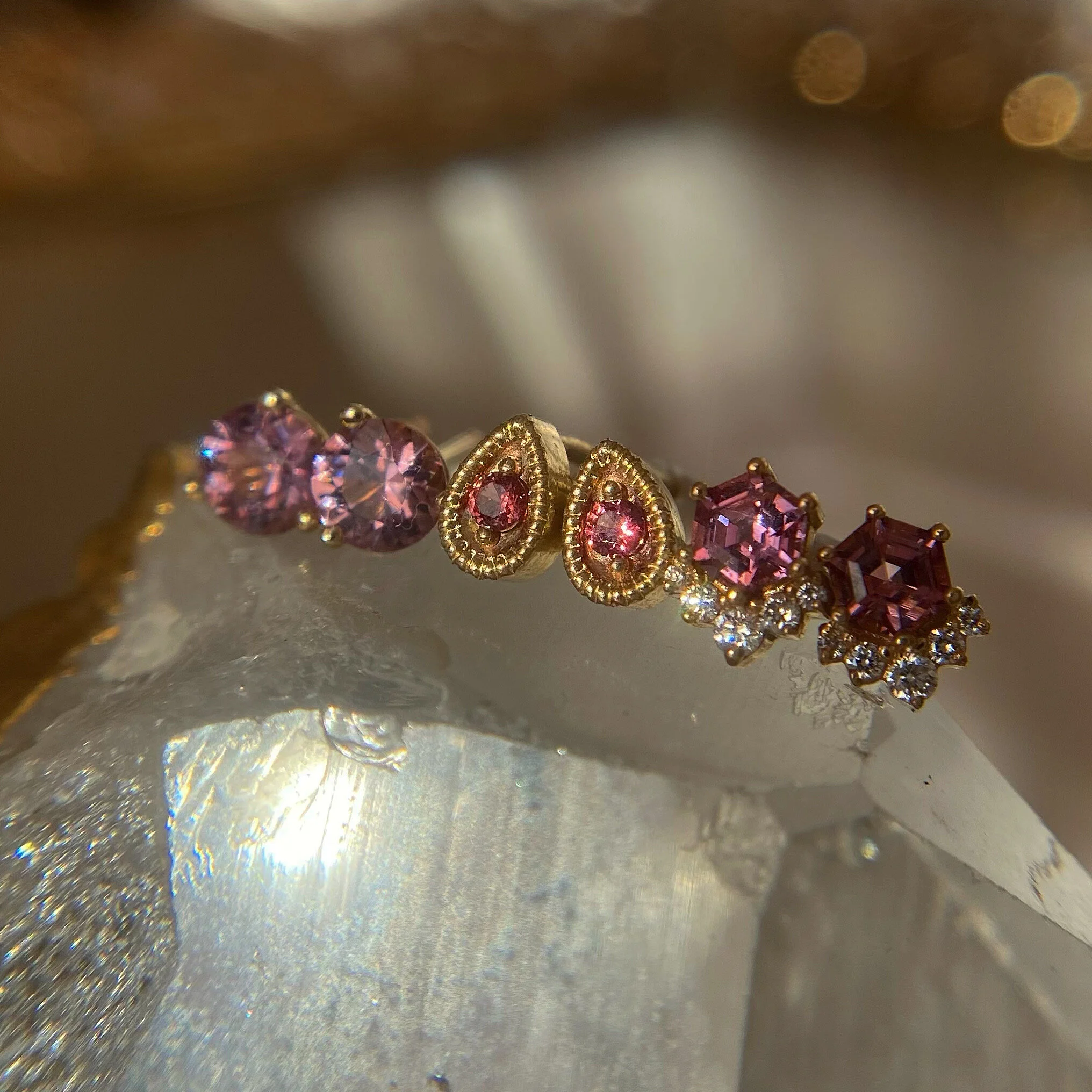 three pairs of pink gemstone and diamond earrings on top of a quartz crystal