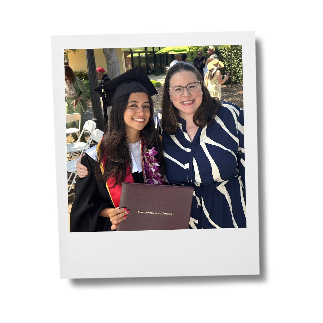 Two women smiling while one wears a cap and gown, holding a diploma