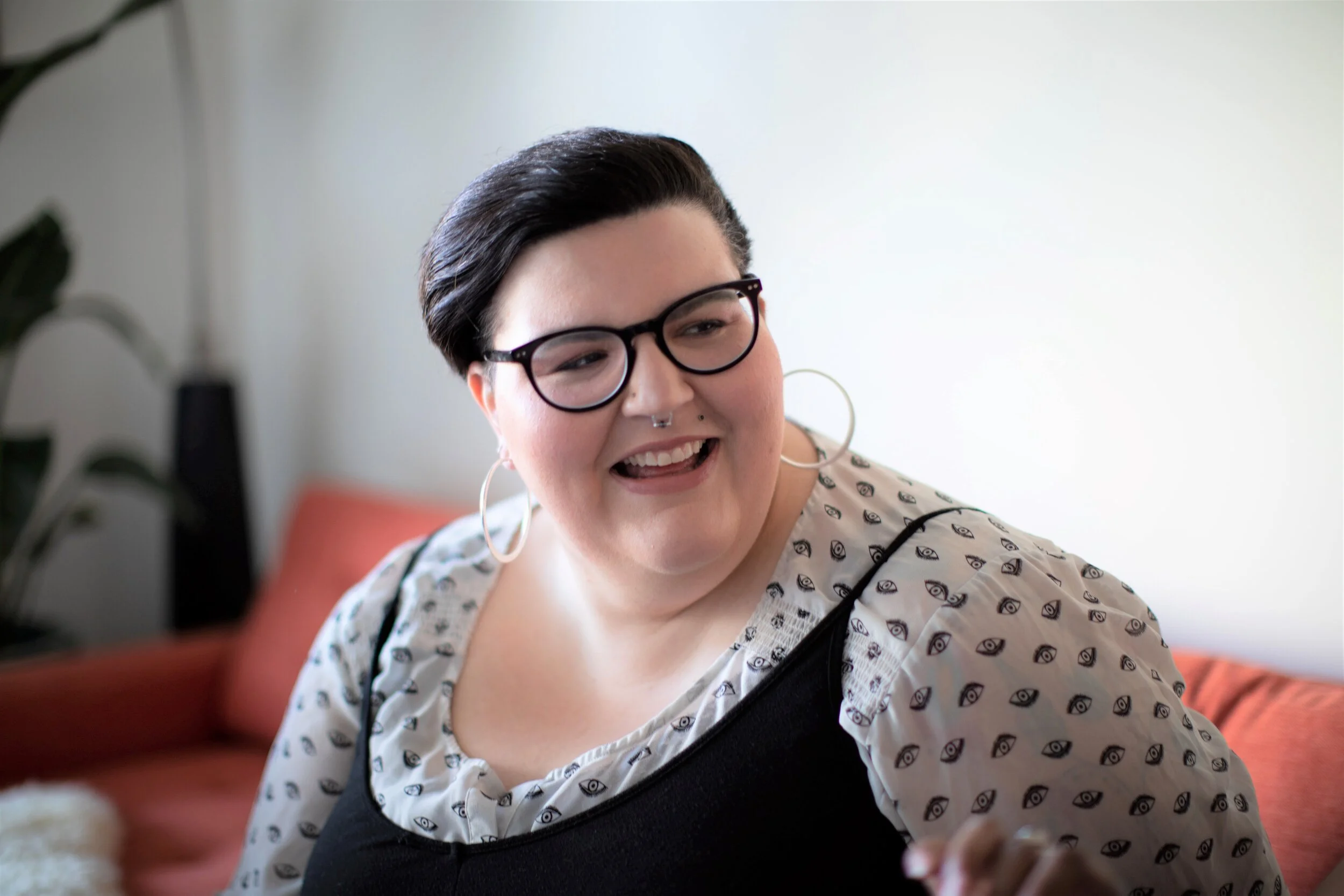 A person wearing glasses while looking to the side and laughing