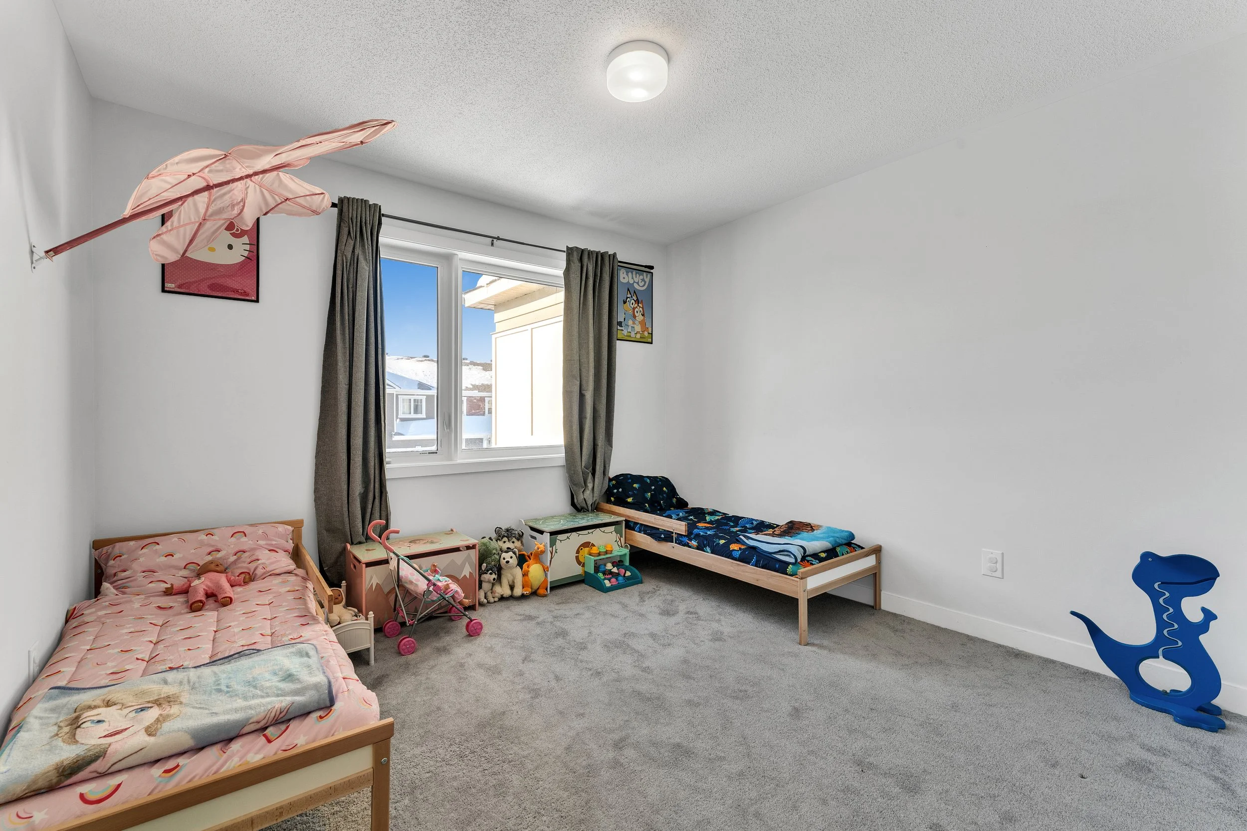 NV3D Real Estate Photography Ottawa  Child's bedroom with two beds, toys, and decor, window showing snowy houses outside