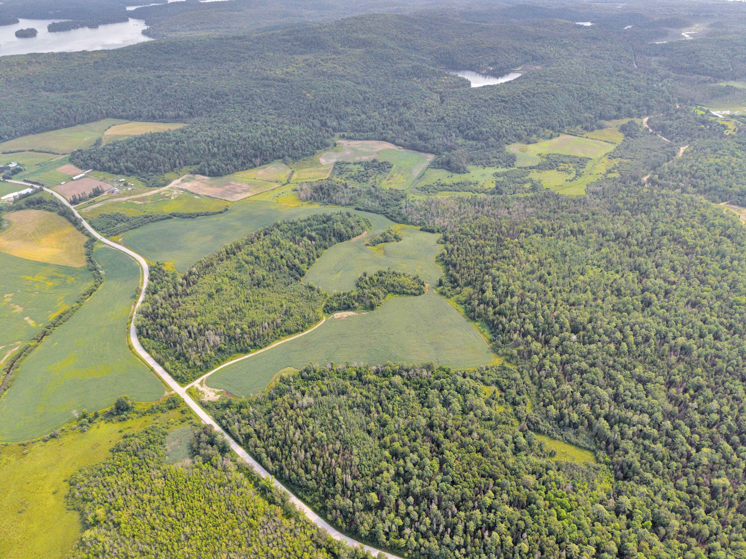 Aerial view of a rural landscape with fields, forests, roads, and lakes.