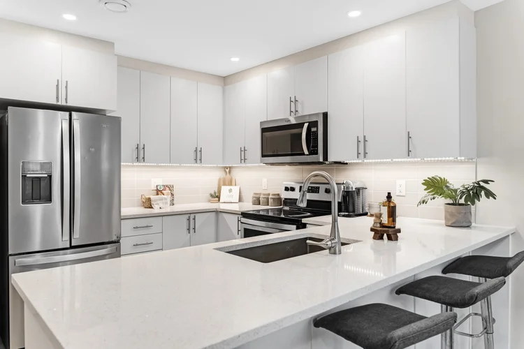 Clean kitchen with clear counters, white cabinets and neatly aligned island stools