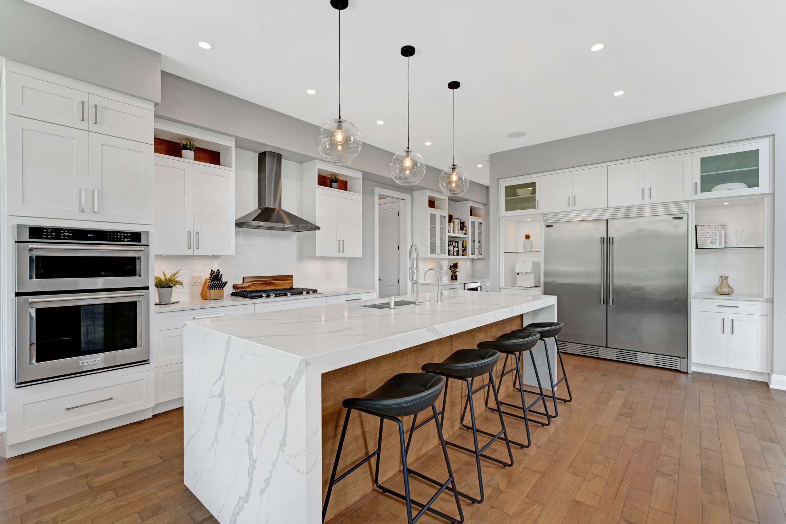 Bright kitchen with a large island, white cabinetry and pendant lighting
