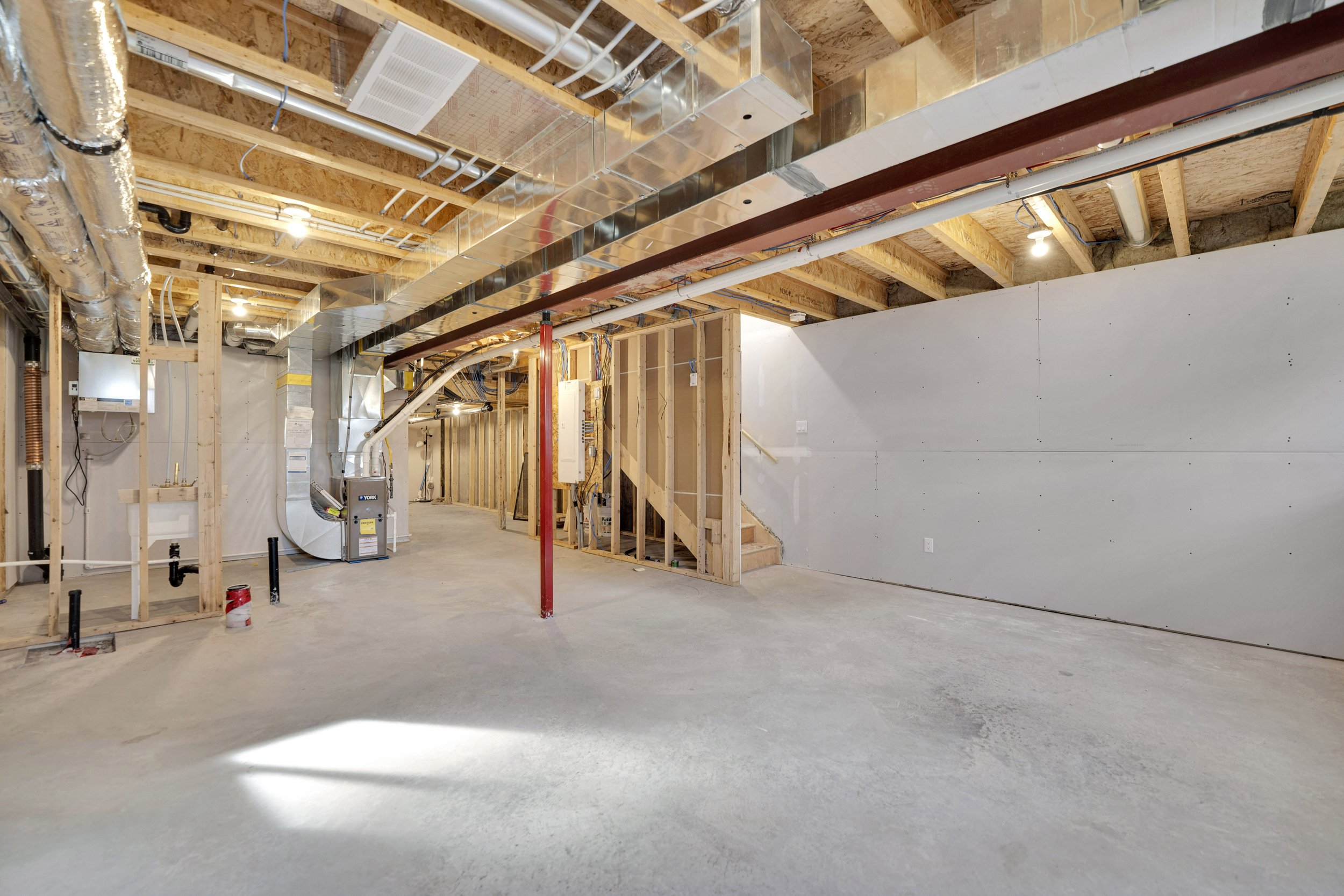 NVISION3D Real Estate Photography Ottawa  Interior view of an unfinished basement with exposed wooden framing, ductwork, and utility pipes, with concrete floor and some wall insulation