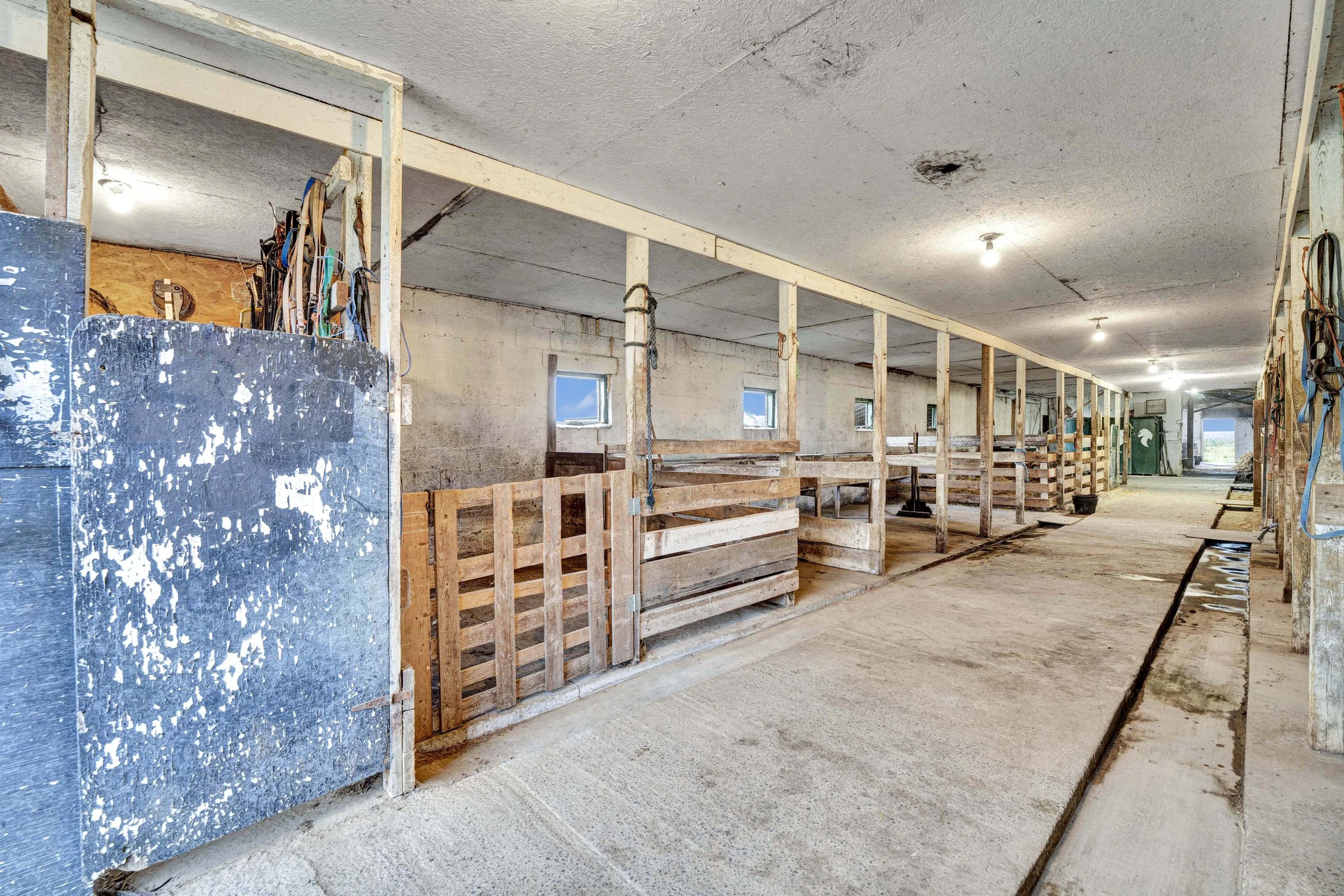 Interior of a building under construction with exposed wooden framing, small windows, and a concrete floor.