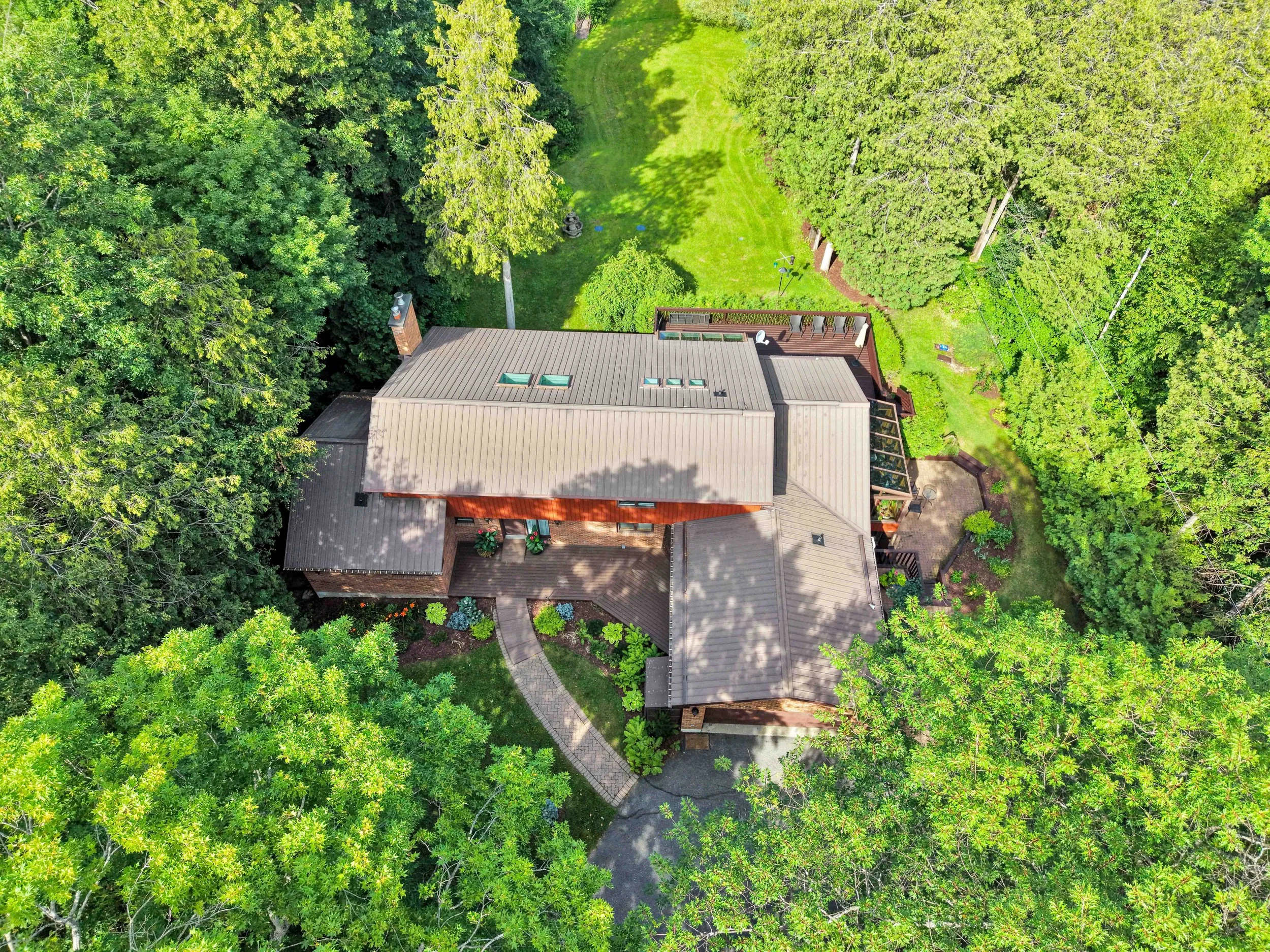 Ottawa Real Estate Photographer Aerial view of a house surrounded by lush green trees and a well-maintained lawn.