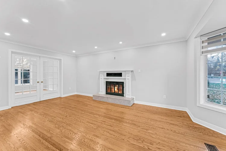 Living room with hardwood flooring, large windows and a white fireplace