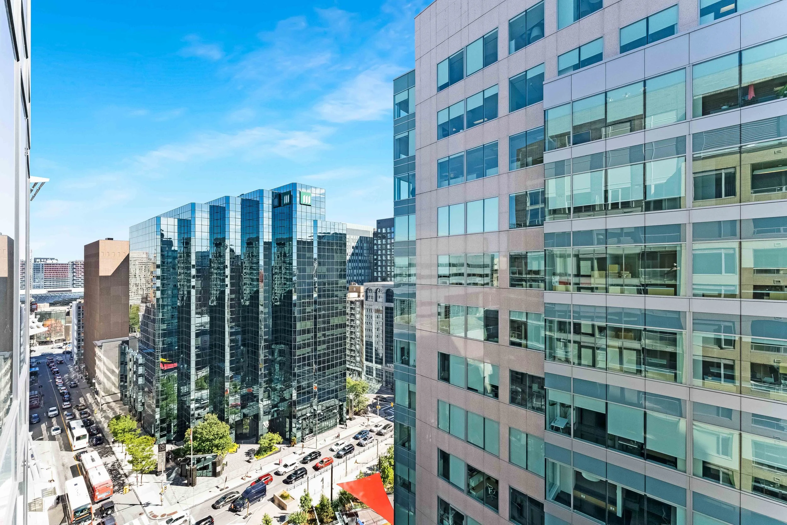 NV3D Ottawa Real Estate Photography View of a city block with modern glass high-rise buildings, streets with cars, and a clear blue sky.