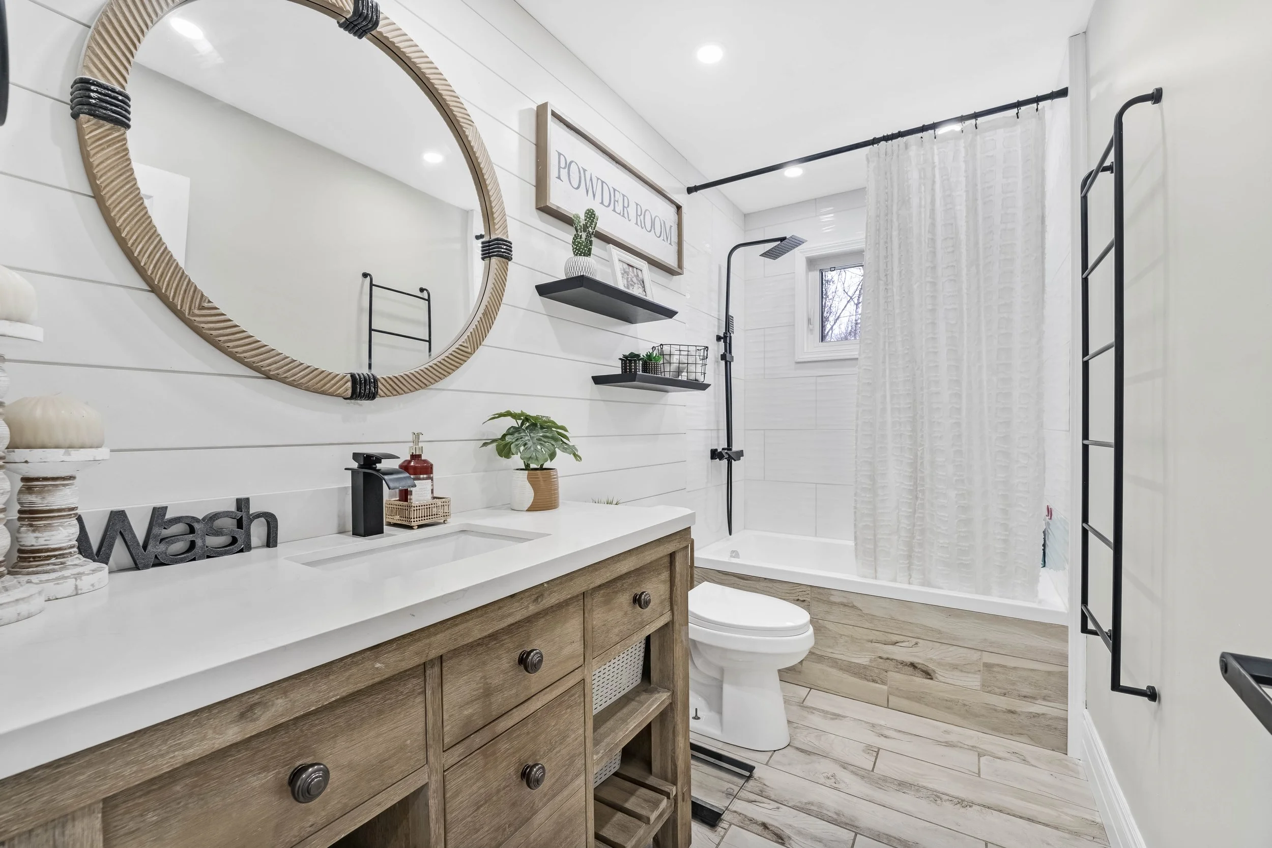  Real Estate Photography in Ottawa Bathroom with a vanity, a mirror, a toilet, a bathtub with a shower, wall-mounted shelves, and decor in neutral tones