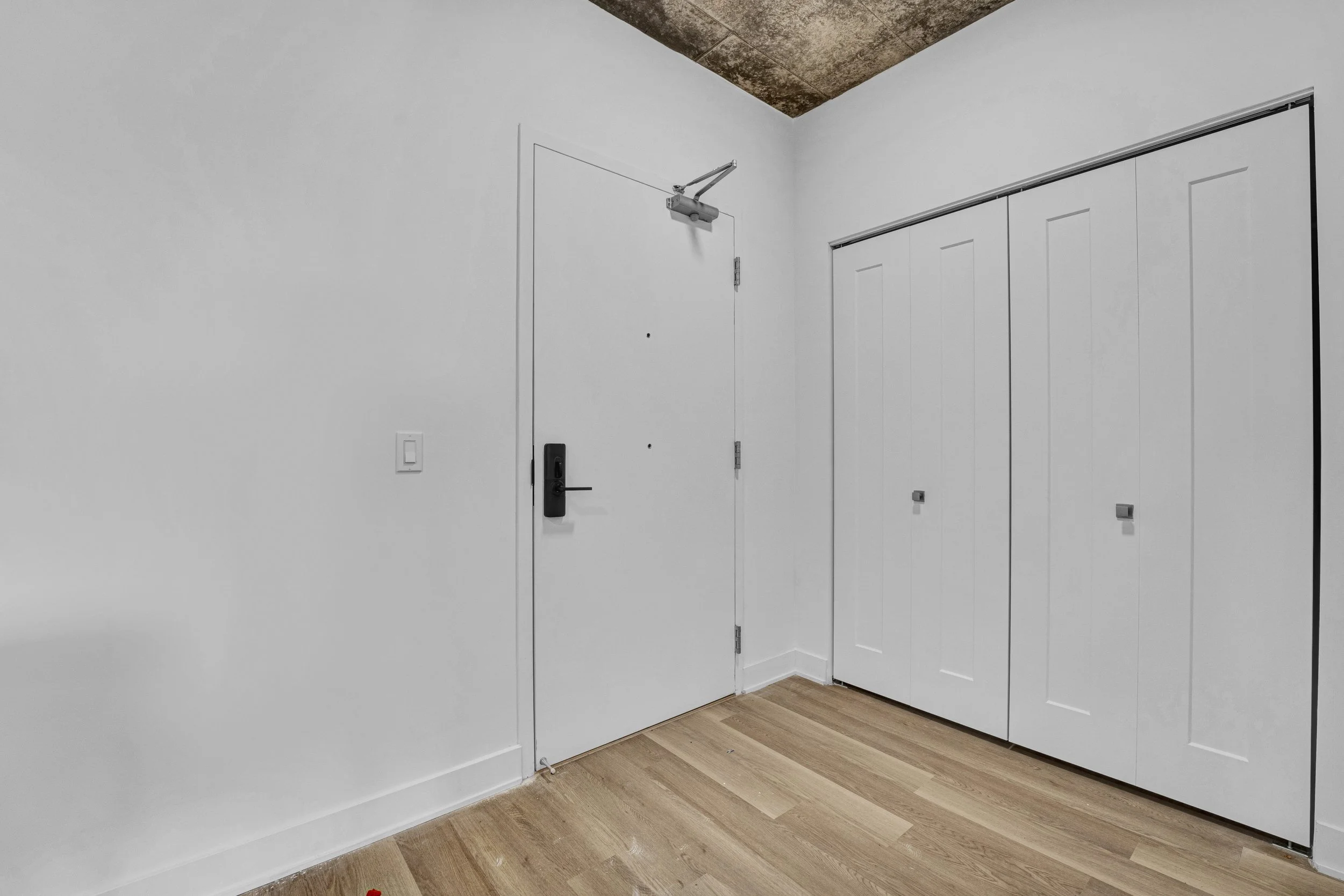 Ottawa Real Estate NVISION 3D  White wall with a door and a closed closet with sliding doors in a room with wooden flooring. Ottawa Photographer