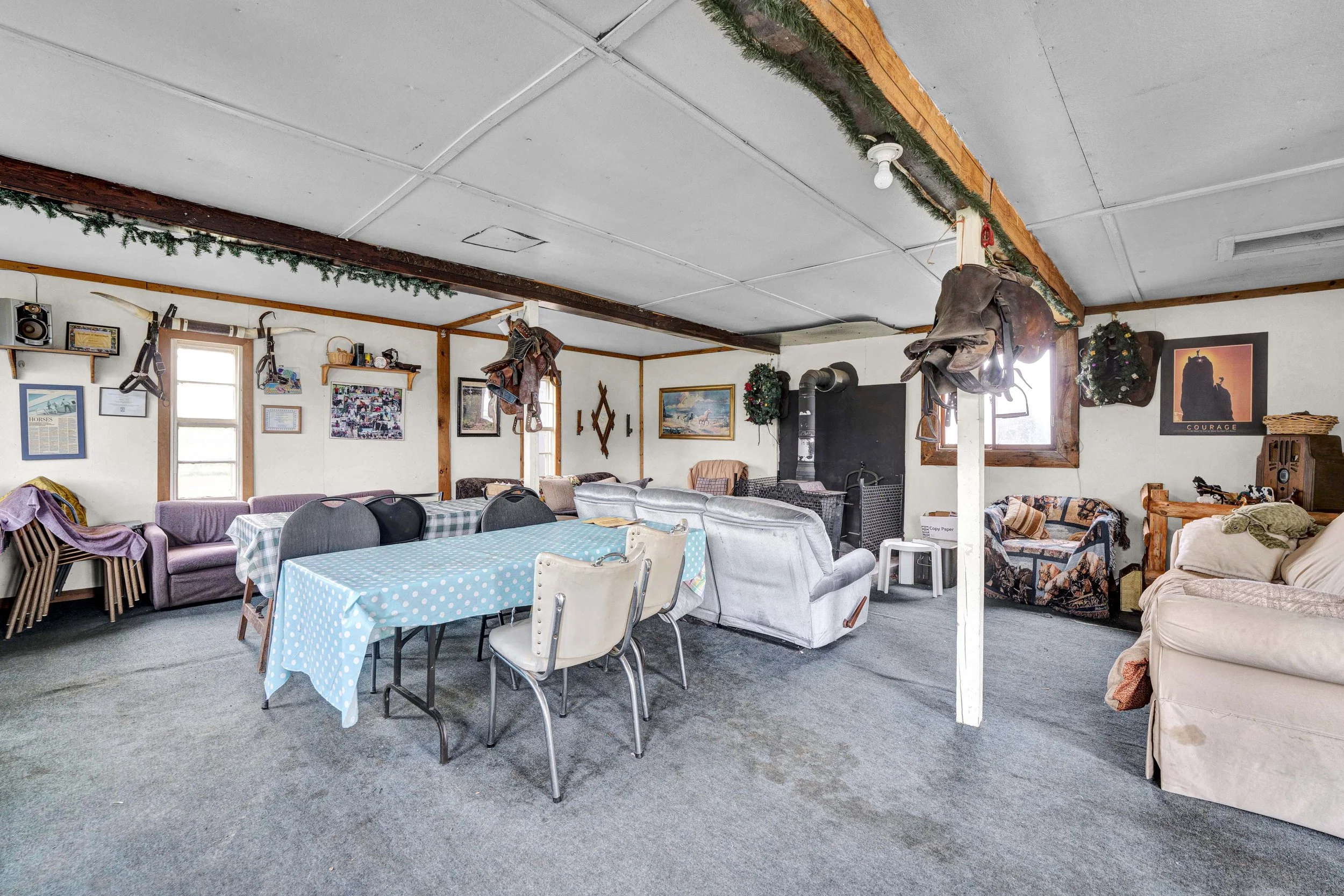 A large indoor space decorated with holiday garlands, featuring various furniture including couches, chairs, and tables, with wall art and decorations.