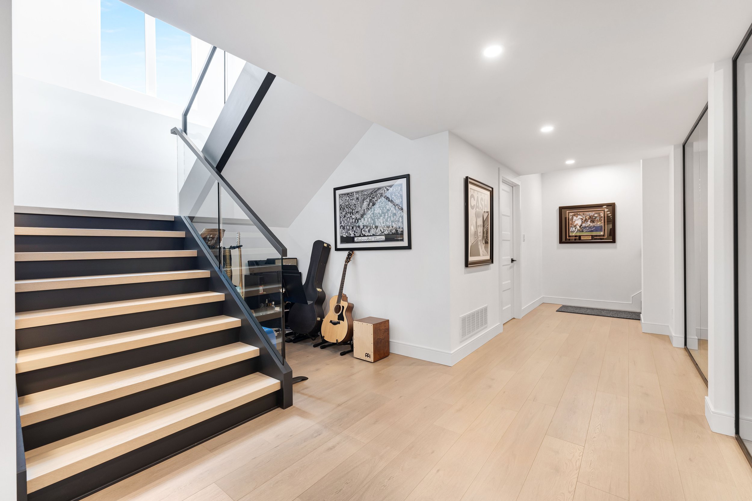 Modern interior with staircase, wooden flooring, and musical instruments.