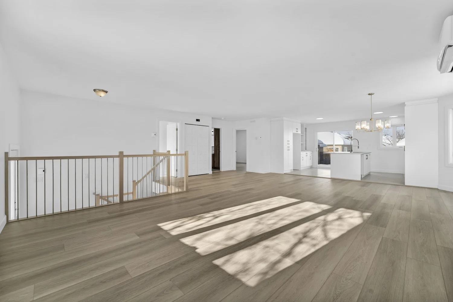 Original photo of an empty living and dining area with light wood flooring