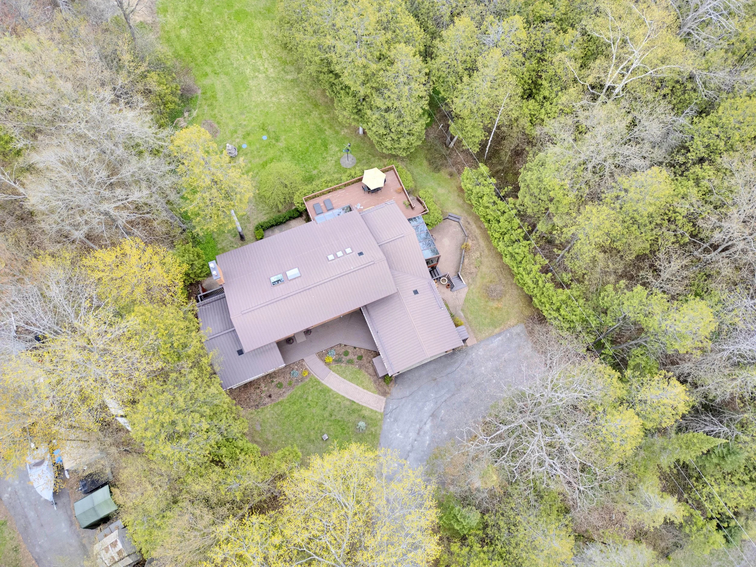 Ottawa Real Estate Media Services  Aerial view of a house surrounded by trees, a green lawn, and a driveway.