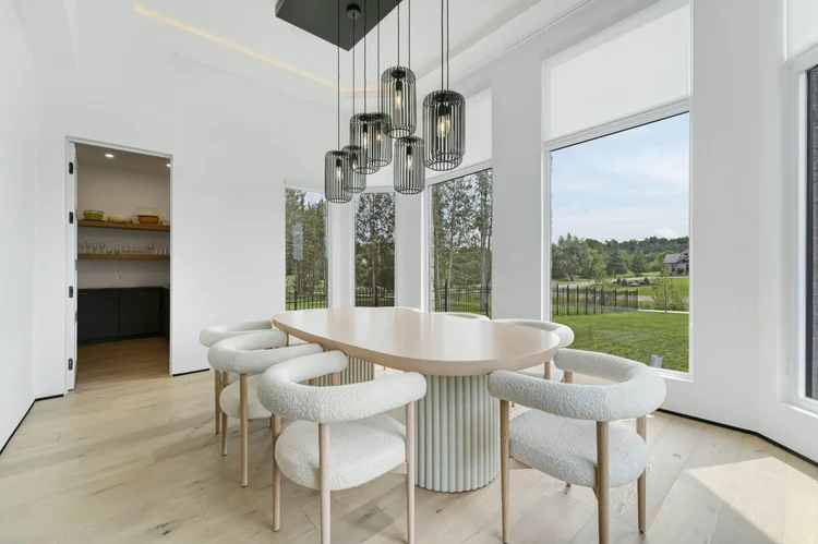 Modern dining room with an oval table, white upholstered chairs and pendant lights