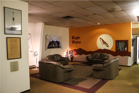 Eagle Plains Hotel lobby, brown puffy couches, one orange wall with Eagle Plains Hotel logo, pictures hanging on white walls