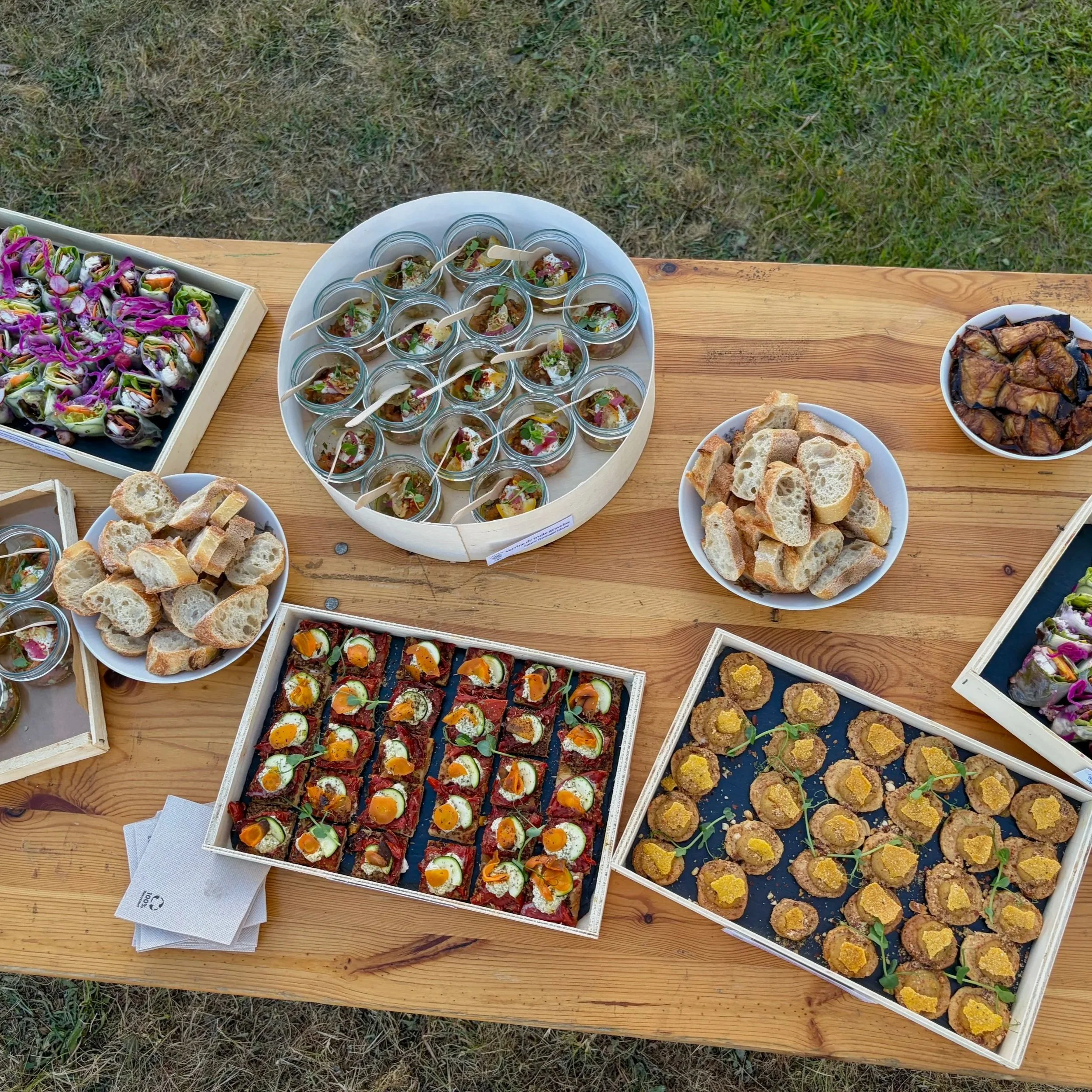Plateaux de petites bouchées végétariennes, des muffins et d'autres amuse-bouches, sur une table en bois à l'extérieur.