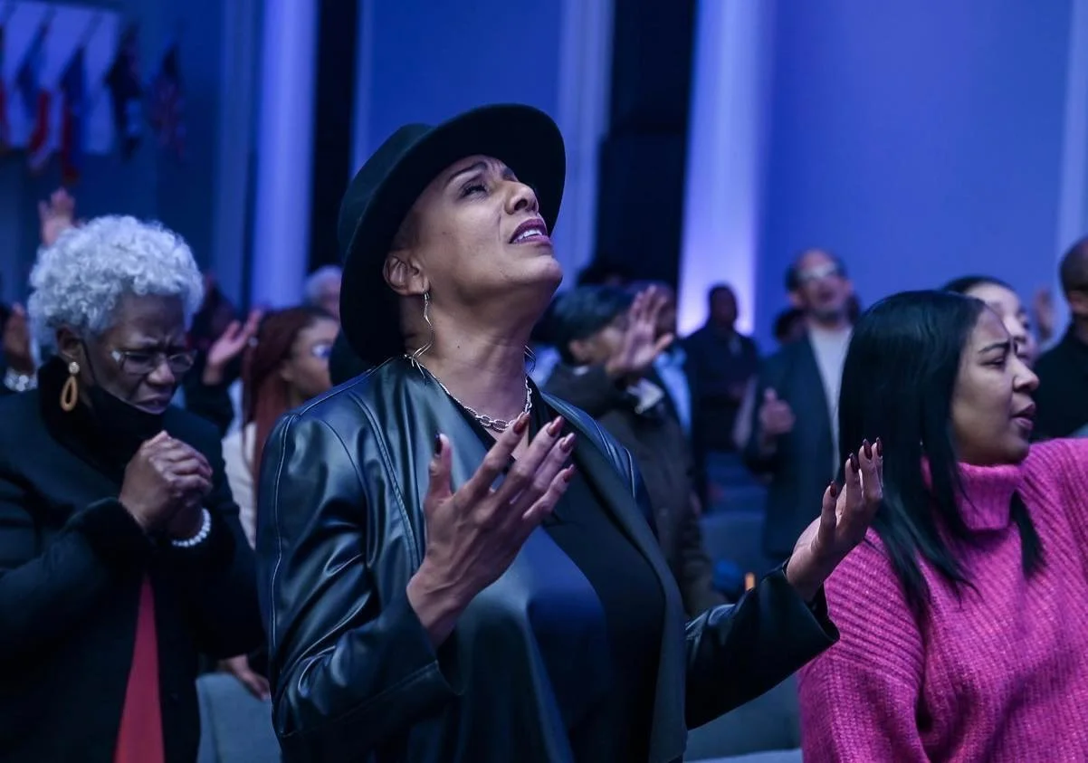 Laurie Sayles praying or worshiping at a religious gathering with blue lighting.