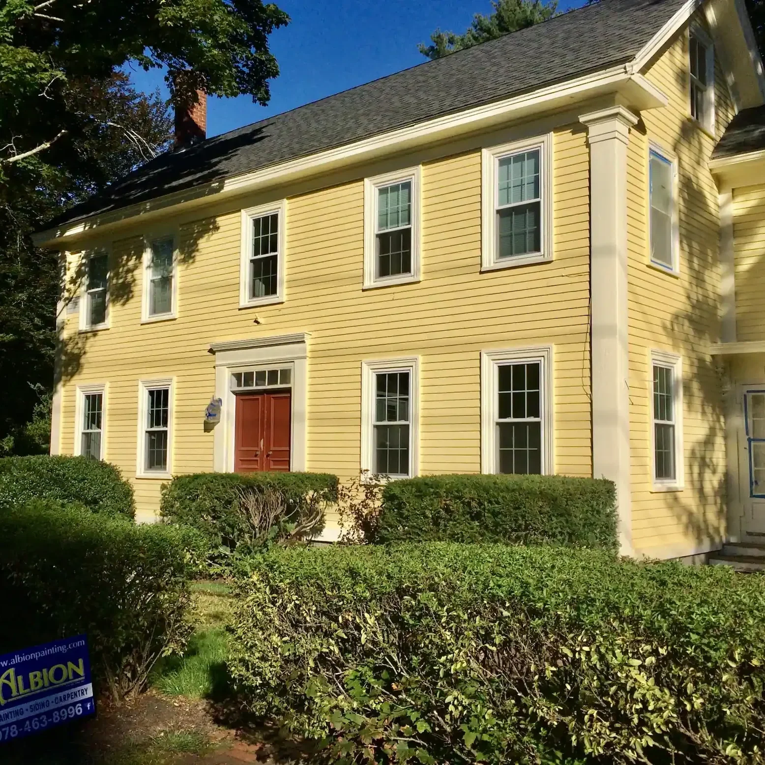 a yellow two story house with a red door in hamilton mass