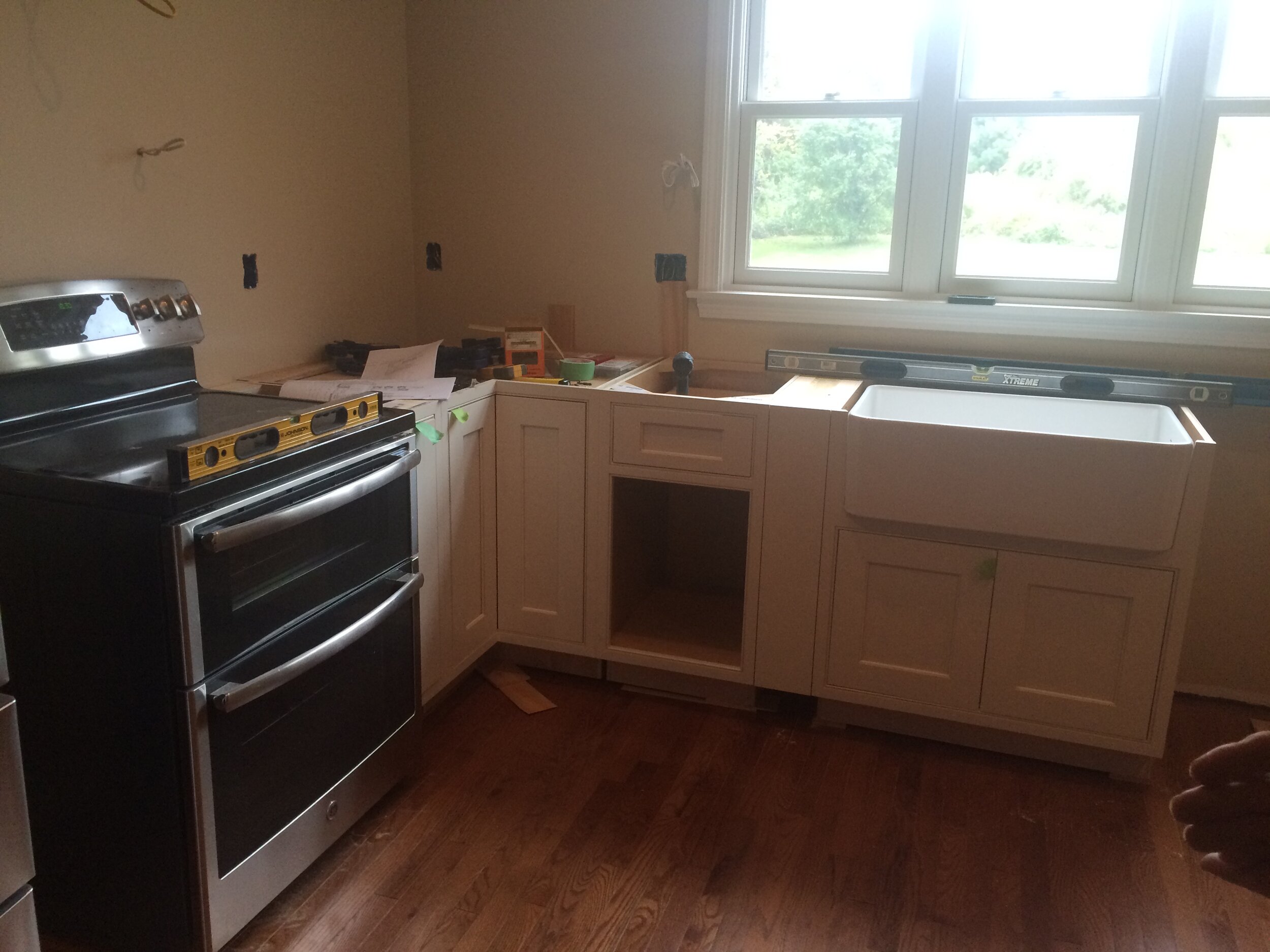 Modern Newburyport Kitchen under renovation with new white cabinetry, a farmhouse sink and granite countertop 