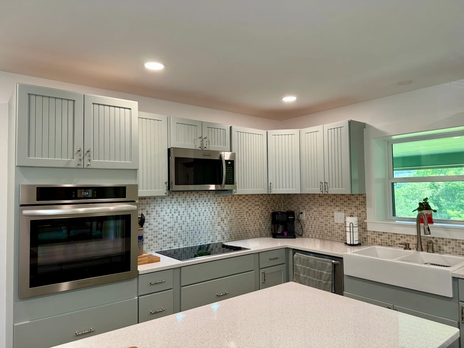 Kitchen remodel with sage green beadboard cabinets, quartz countertops, mosaic tile backsplash, and farmhouse sink — North Shore, MA