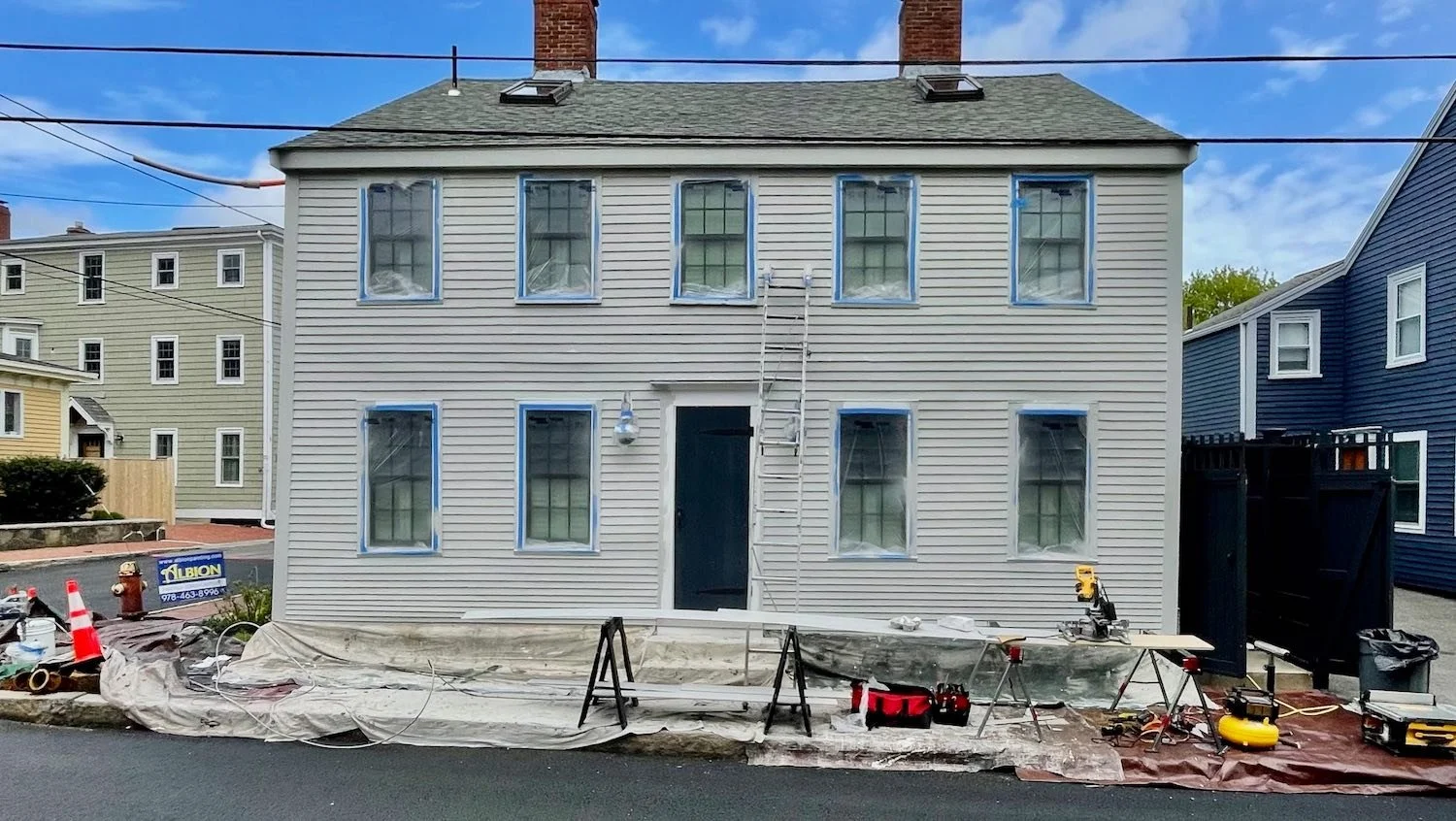 Exterior painting preparation with masked windows and drop cloths on a historic Newburyport MA home by Albion Contracting