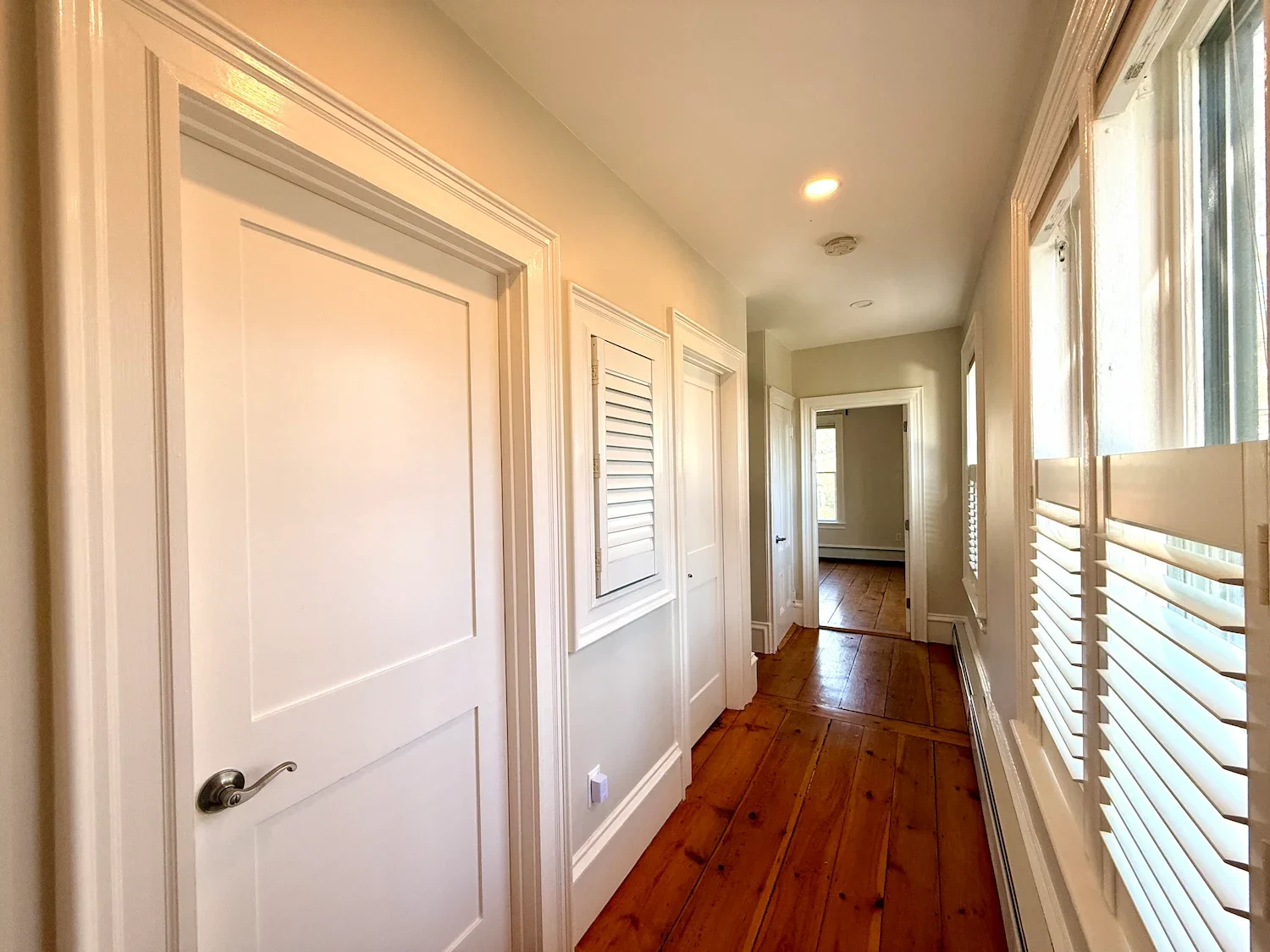 Interior painting with white painted doors, trim, and shutters in a historic home hallway with original pine floors — Newburyport, MA