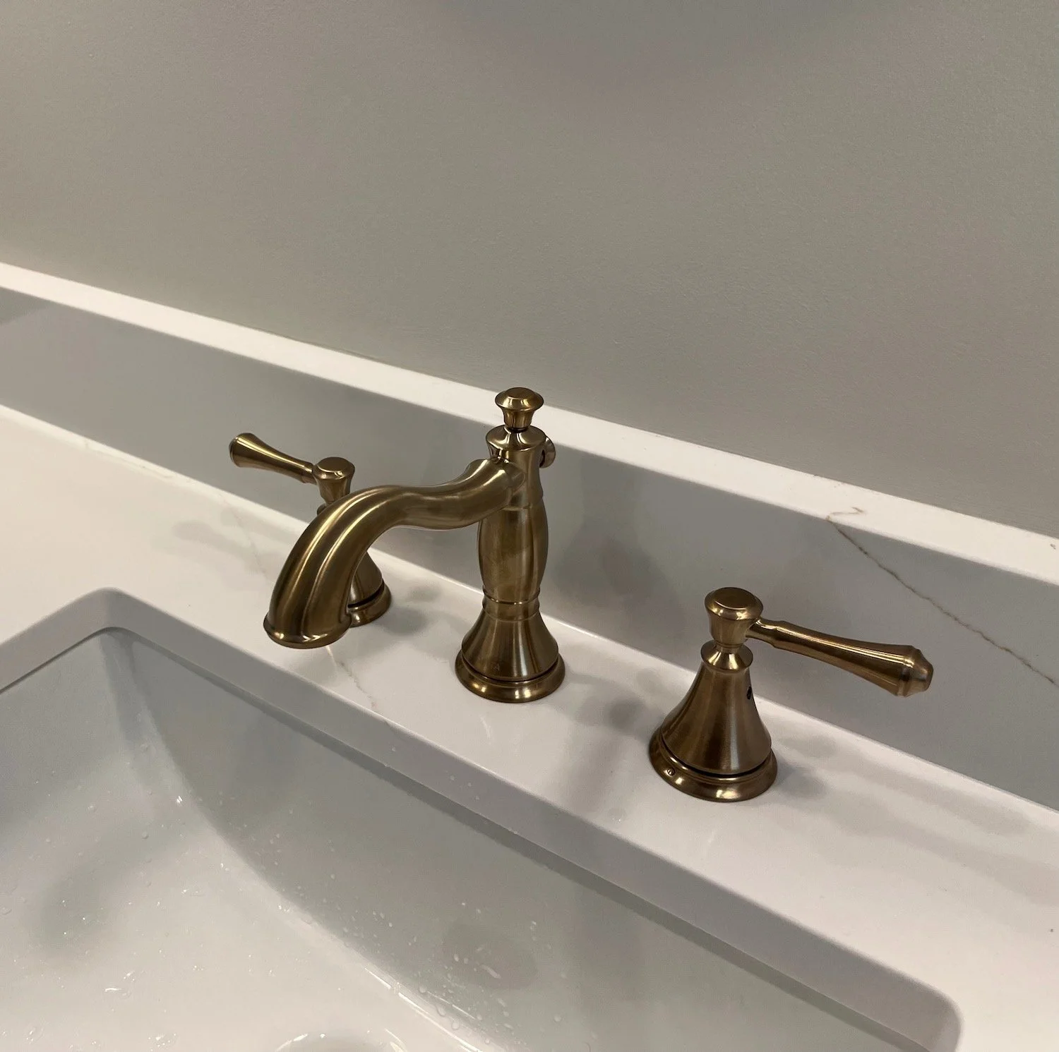 Antique brass faucet and marble countertop detail in a bathroom renovation on the North Shore MA