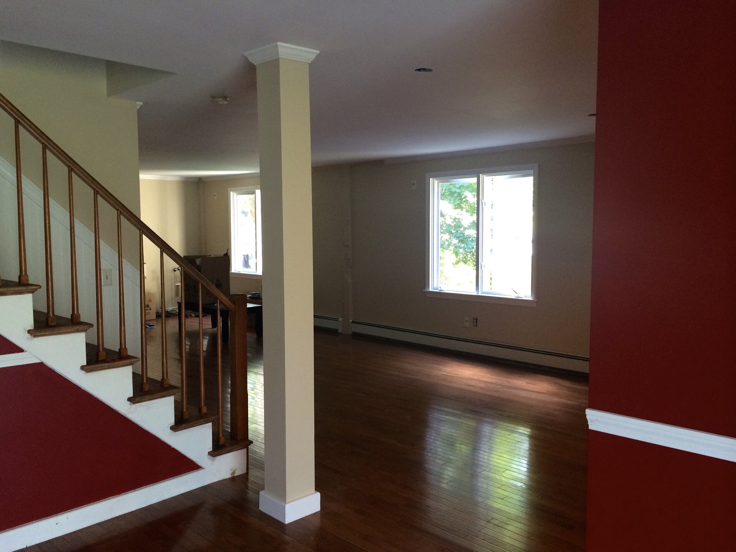Georgetown living room with hardwood floors, white trim, large windows, and red accent wall.
