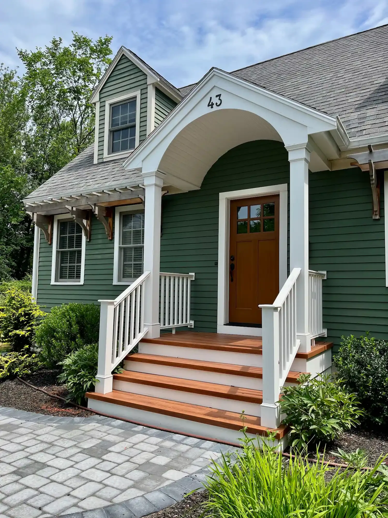 Exterior painting in Salisbury MA — sage green cape with white portico and wood door by Albion Contracting
