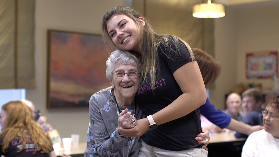 GlamourGals volunteer hugging senior