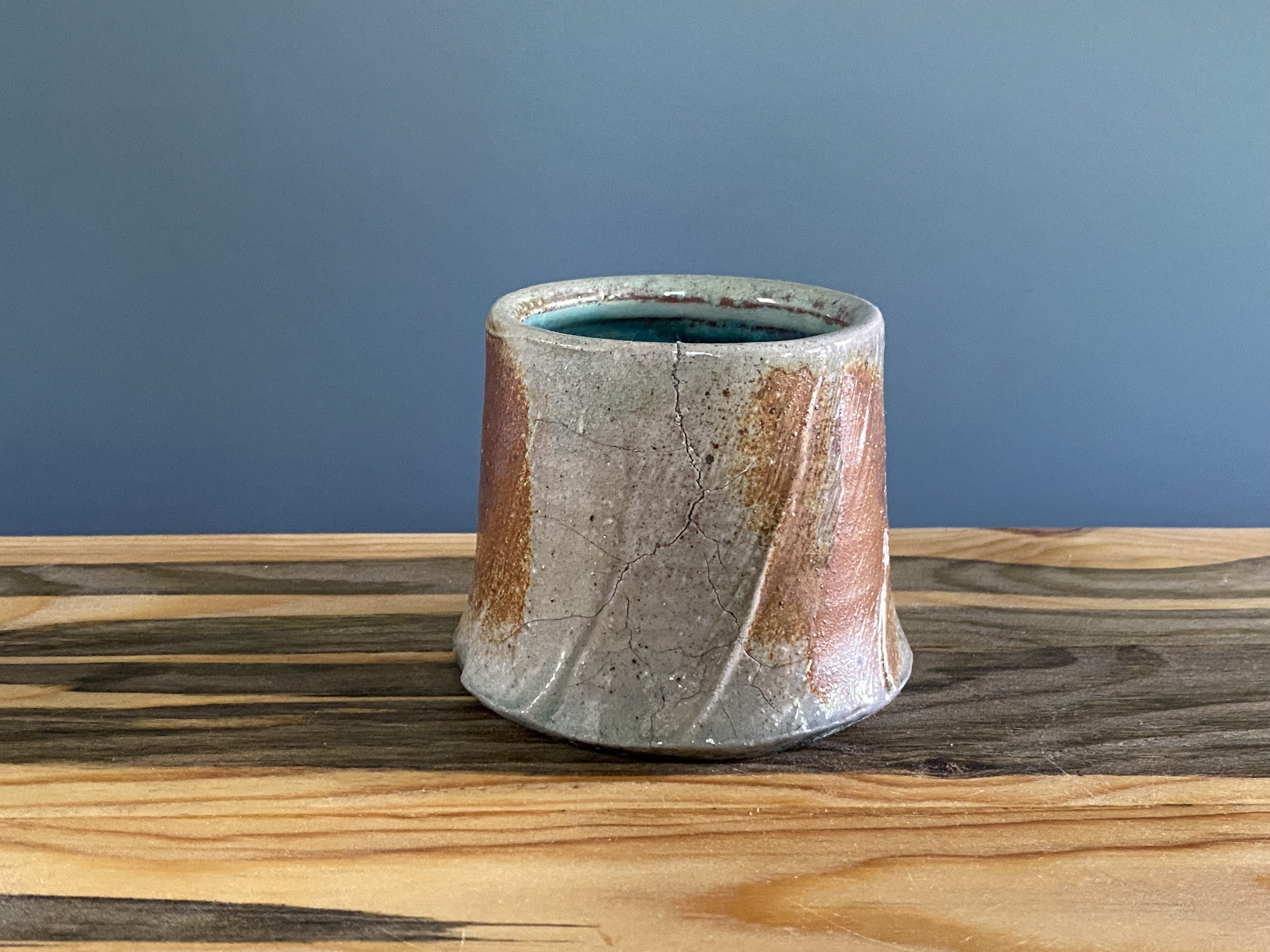 Cup with significant fissure and seal with local clay slip brushed onto exterior