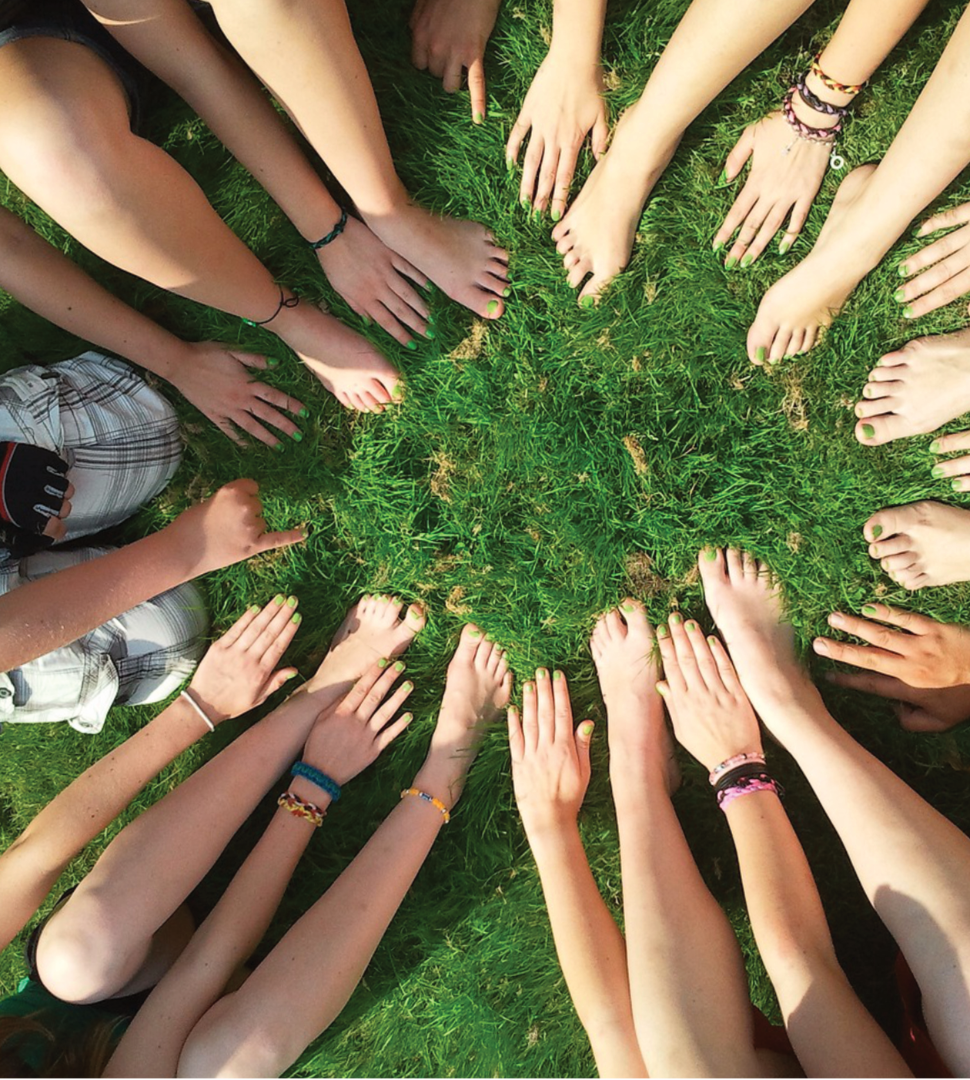 Many hands joined in a circle on the grass – community and social responsibility