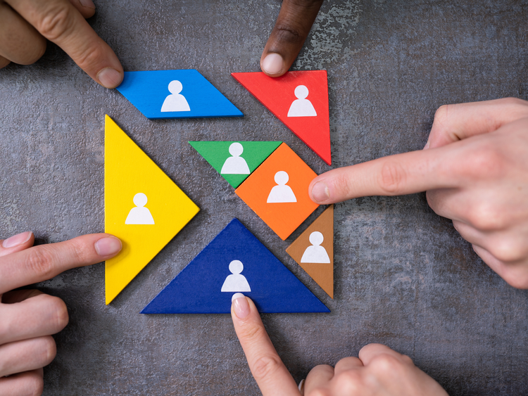 Hands arranging coloured triangles with people – different behavioural styles in a team