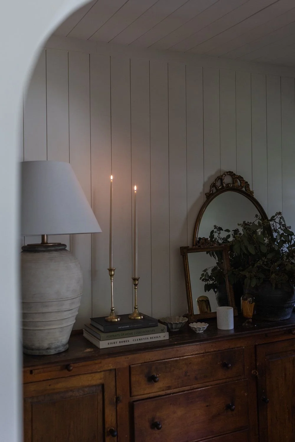 Serene bedroom corner with a vintage lamp, candles, and decorative mirror