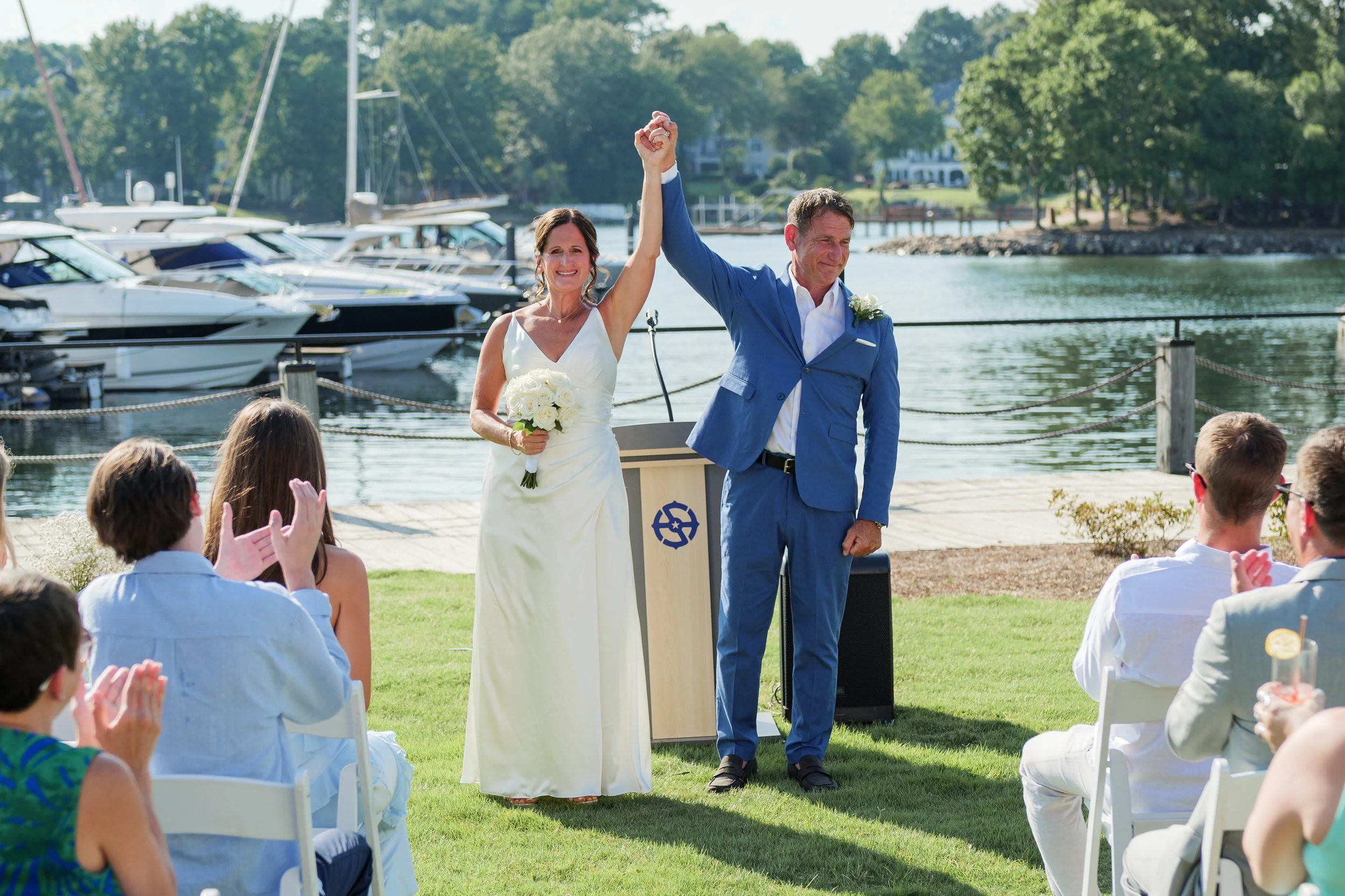 bride and groom holding their hands in the air at wedding ceremony after just getting married at Safe Harbor Peninsula wedding venue