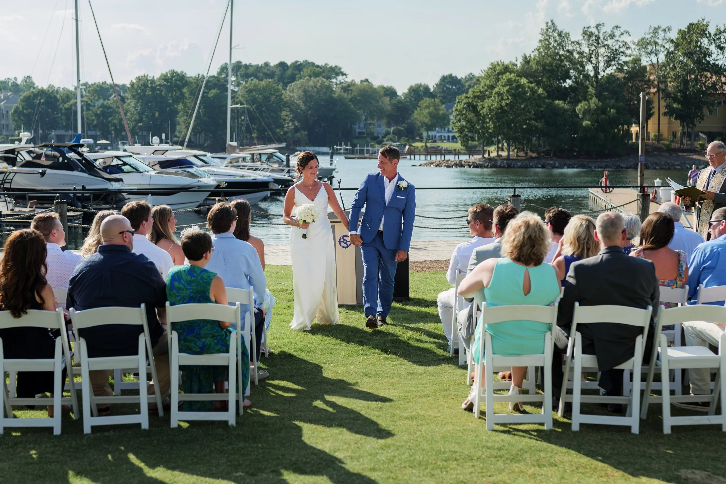 bride and groom holding hands walking down isle after wedding ceremony at Safe Harbor Peninsula wedding venue