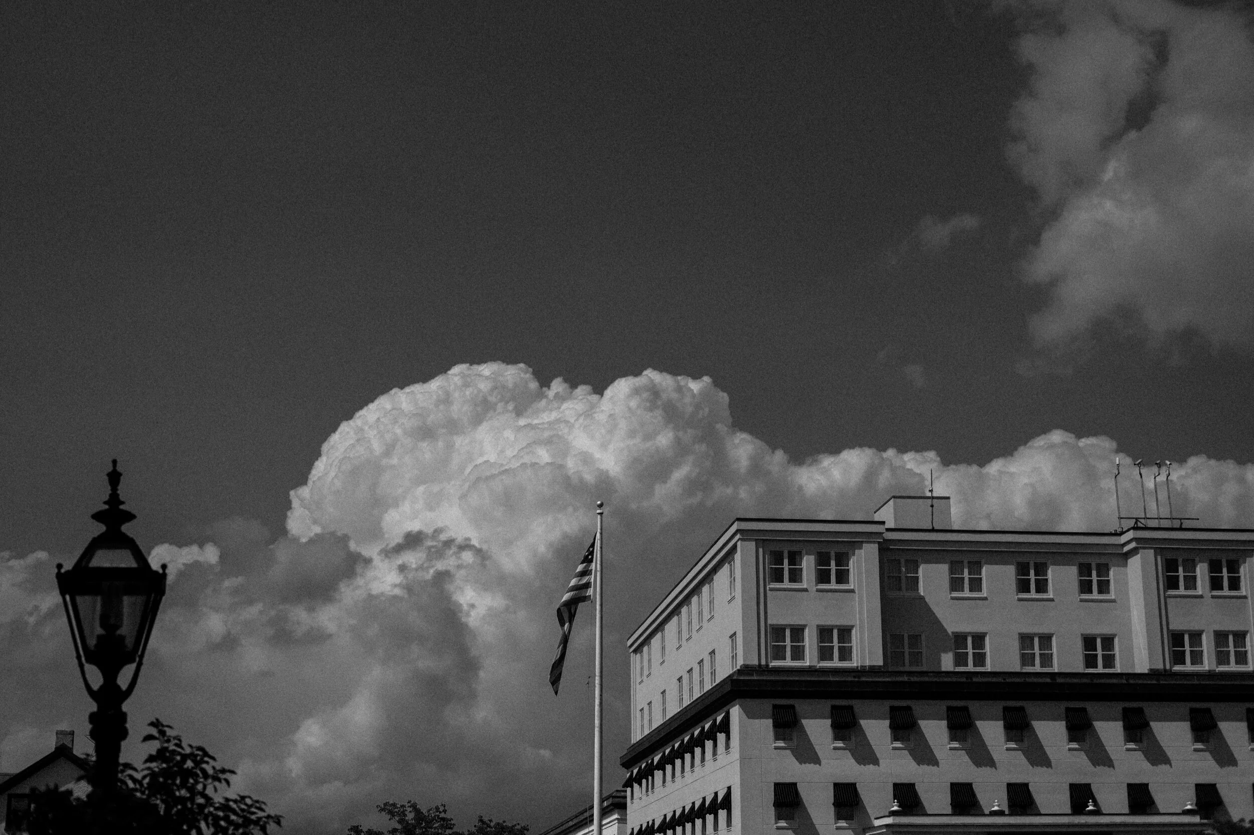 Black and white photo of a building with a flagpole and streetlamp