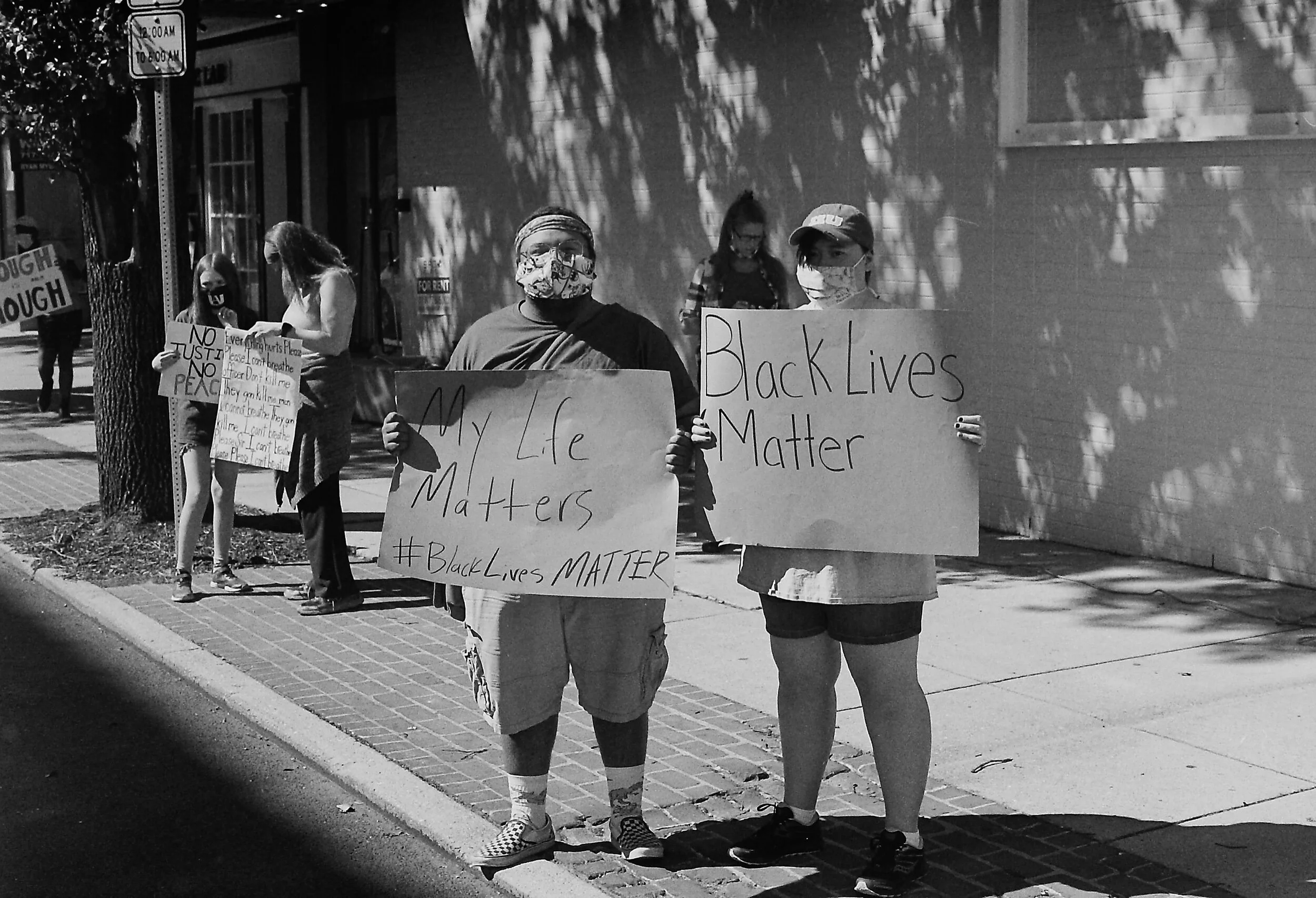 People holding signs at a Black Lives Matter protest on a sidewalk, including messages "My Life Matters" and "Black Lives Matter."