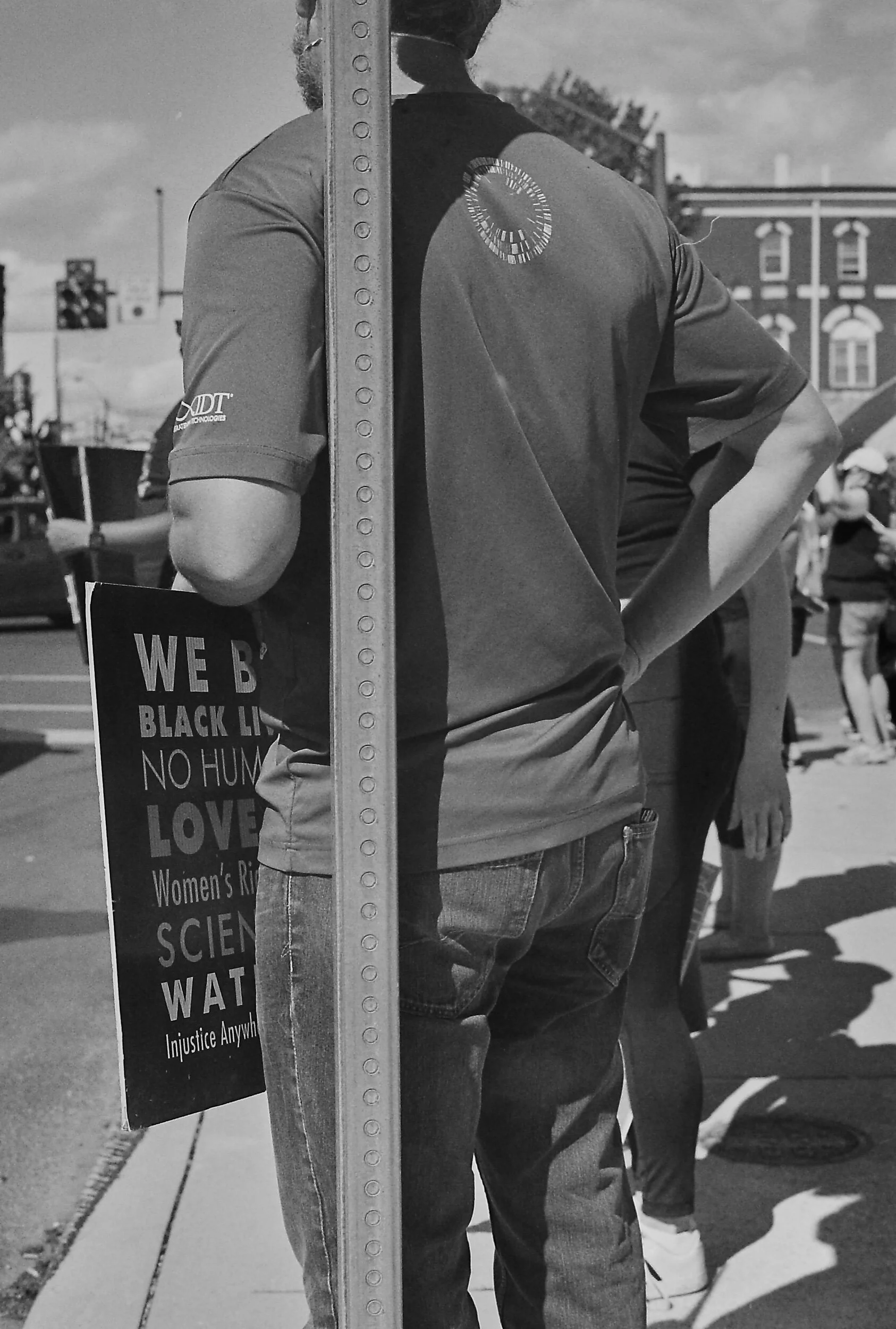 Protesters holding signs with messages supporting equality and justice, standing on a city street.