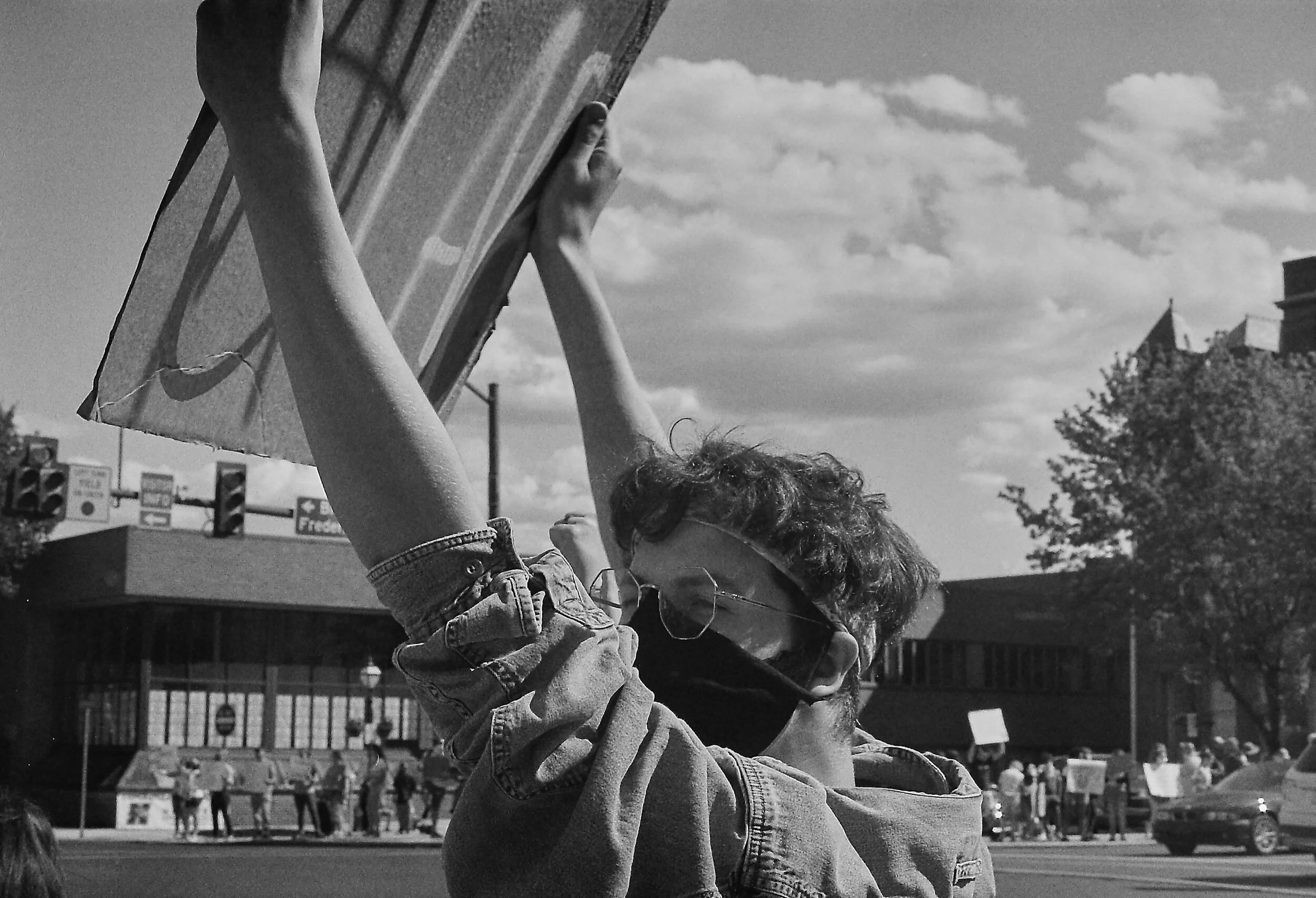 Person wearing a mask holding up a sign at a protest