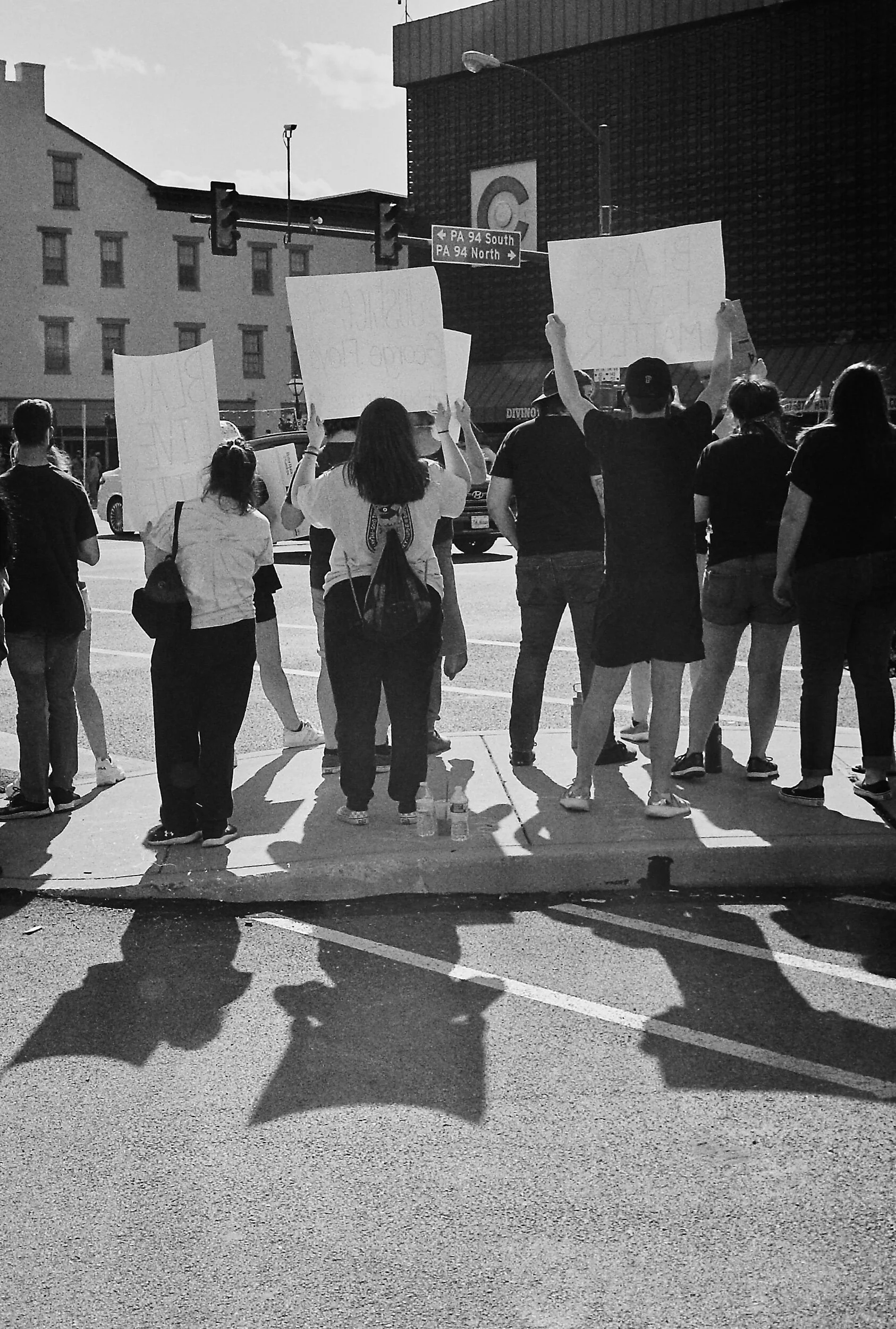 Group of people holding protest signs on a city street corner