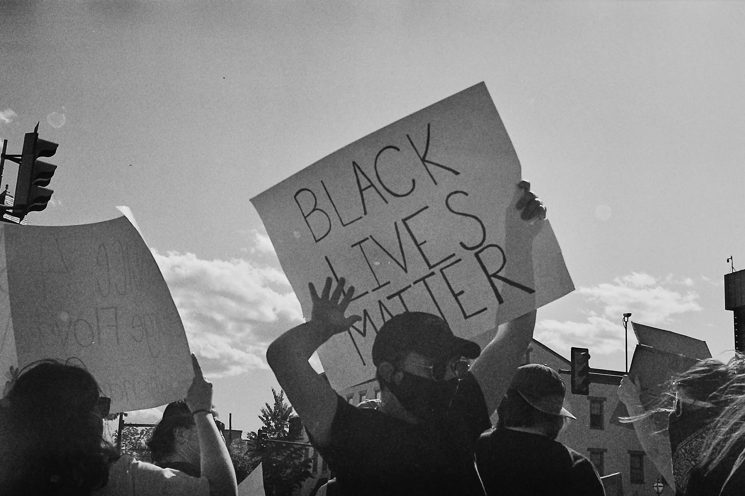 Protesters holding signs with "Black Lives Matter" text outdoors.